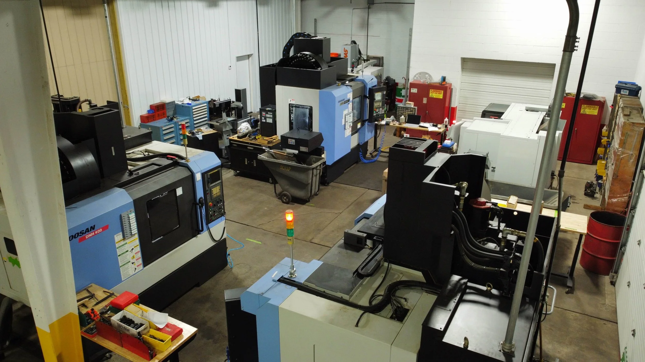 Industrial workshop with various CNC machines, tools, and equipment in a warehouse setting.