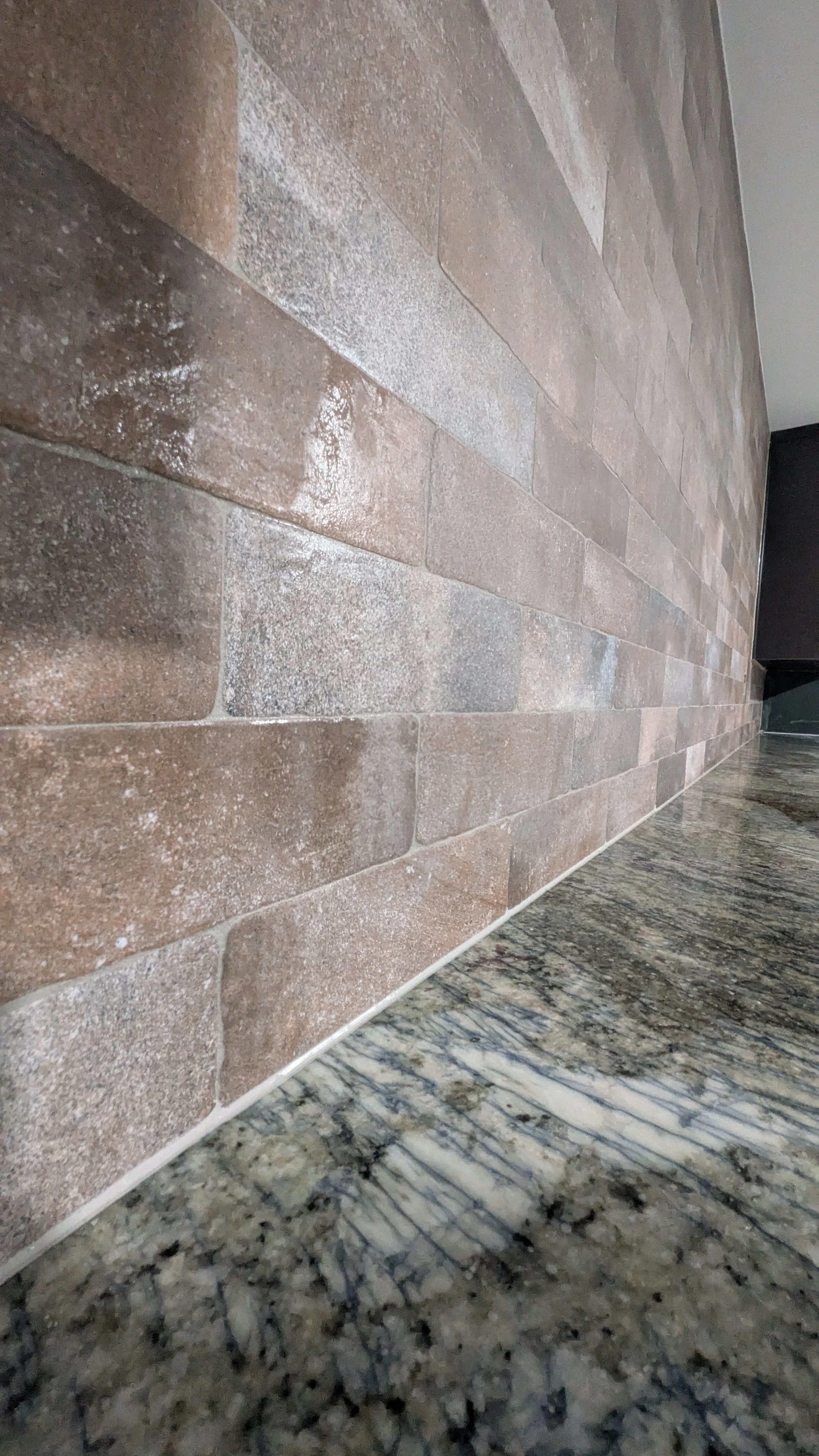 Close-up of a brick wall with a granite countertop at its base.