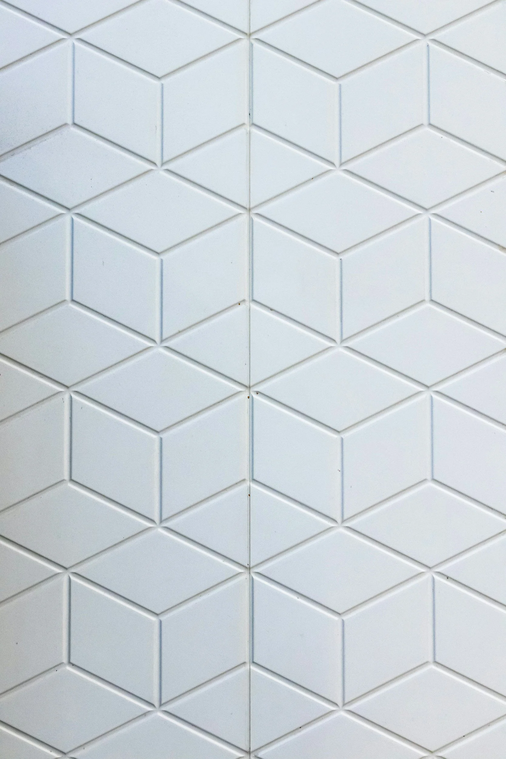 Close-up of white tiled wall with a geometric pattern of hexagon and diamond shapes.