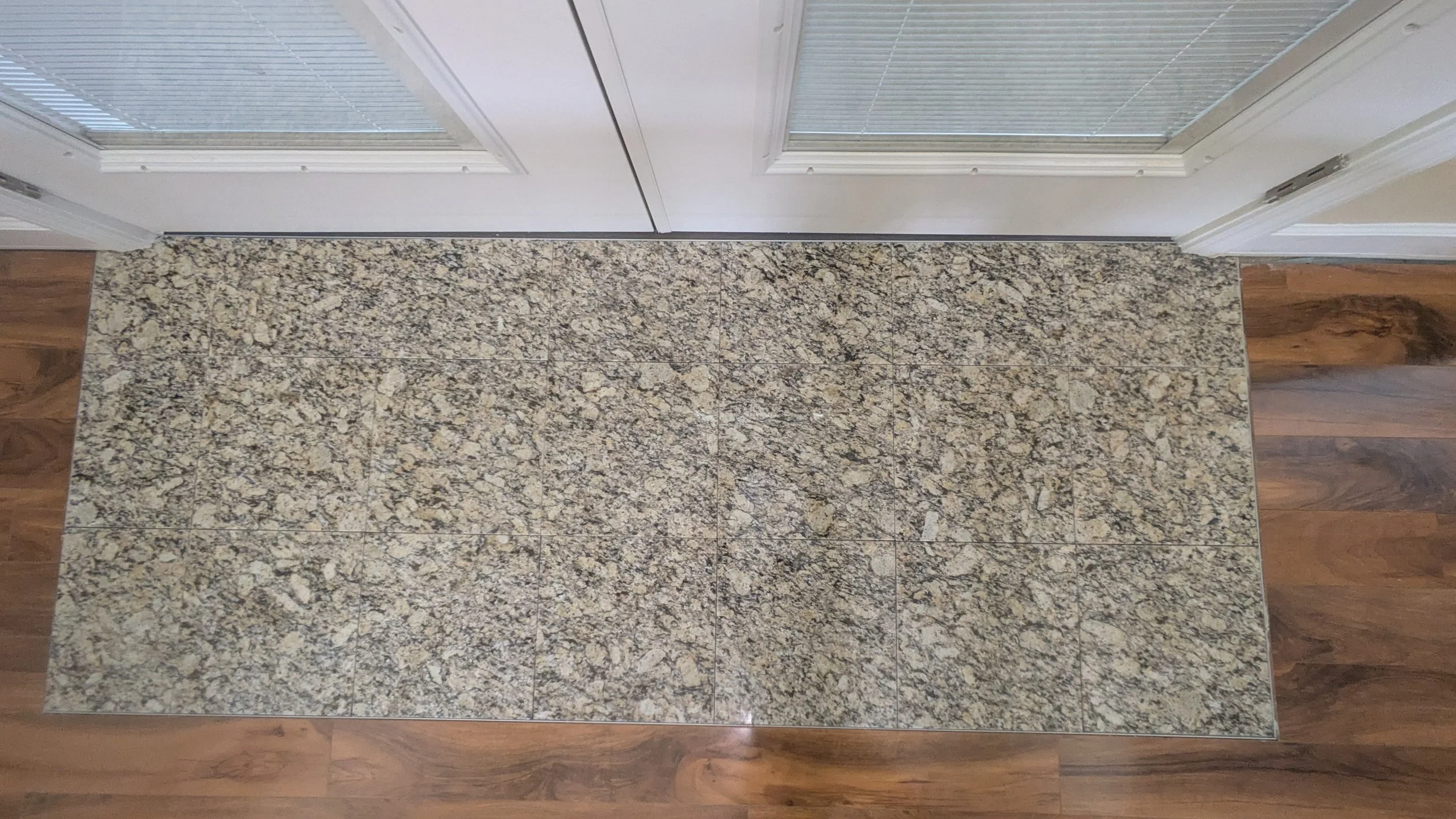 Interior view of a room with granite tile flooring and white paneled doors.