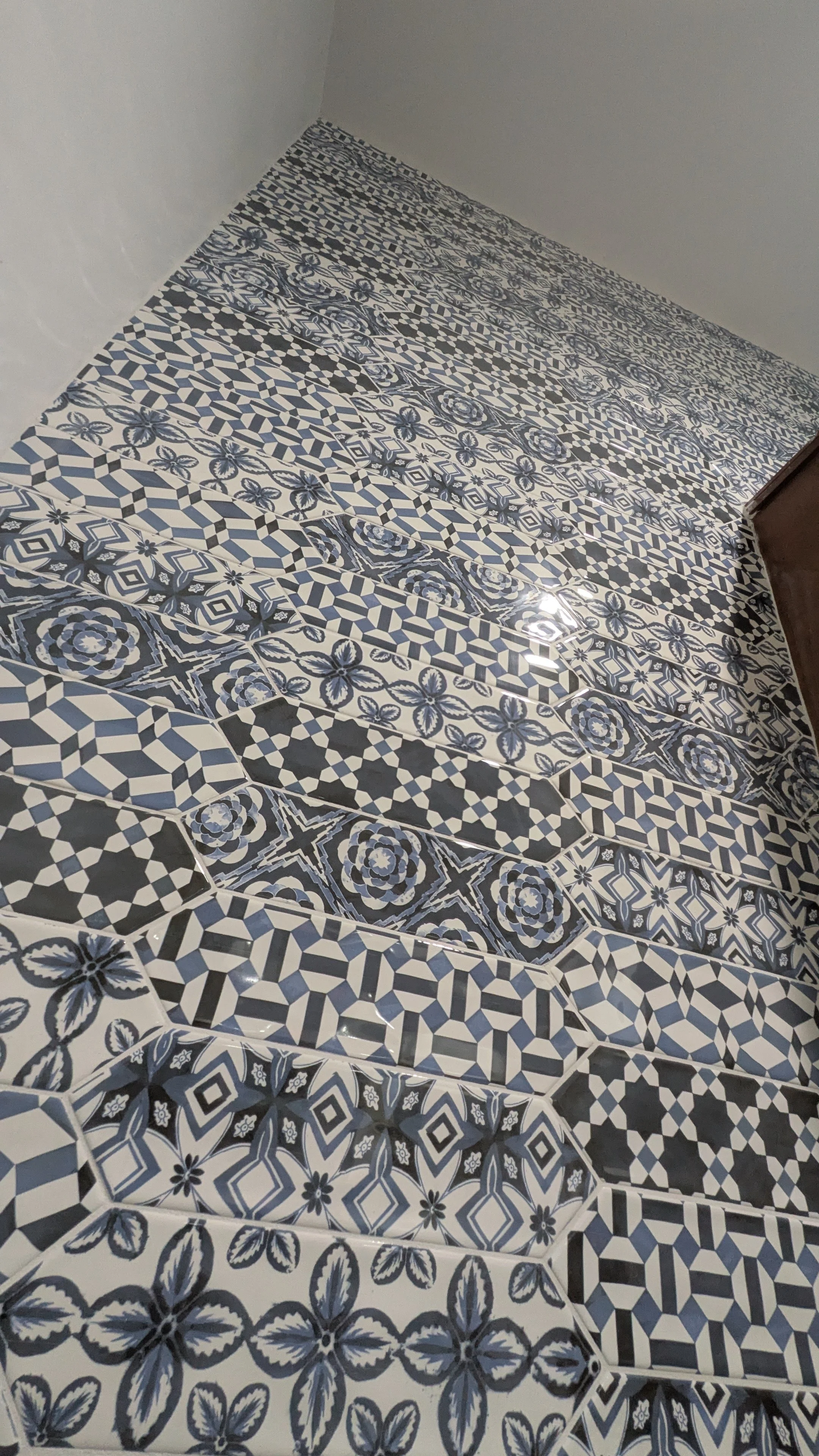 Close-up of a wall with decorative blue and white patterned tiles arranged in horizontal rows.