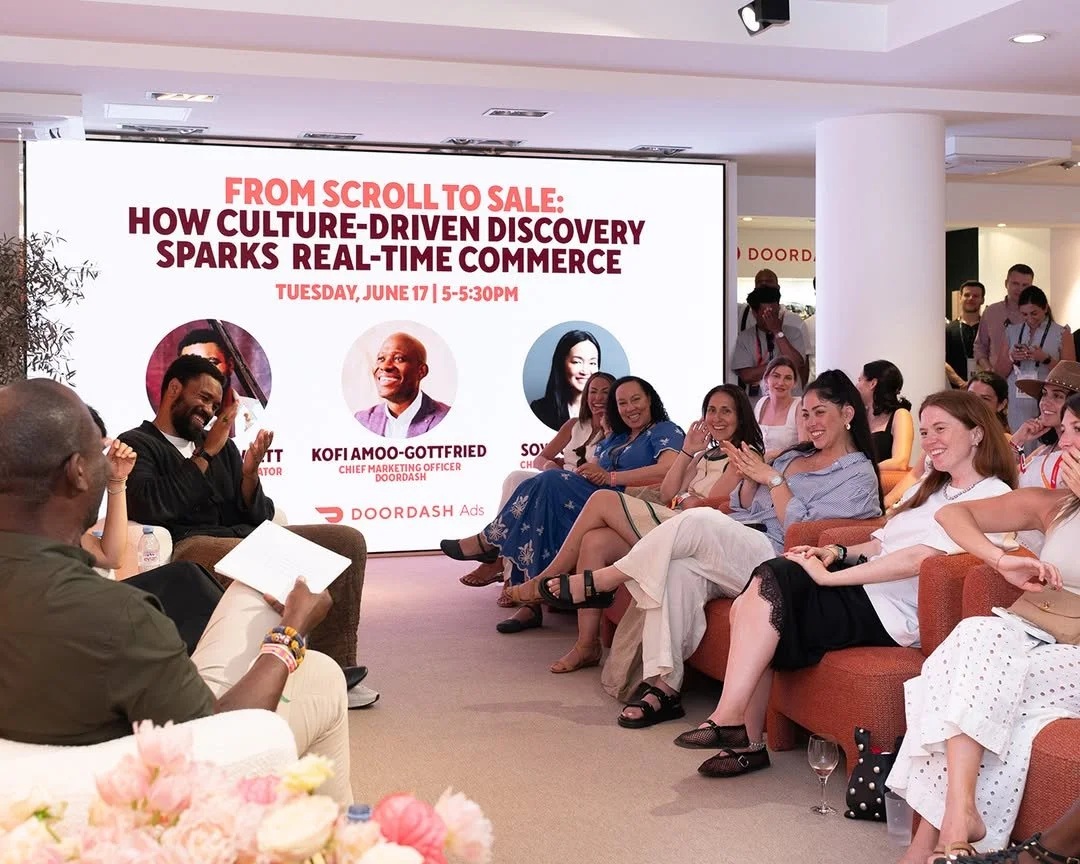 A group of people watching a panel discussion in a modern conference room with a large electronic screen behind them displaying the event details. The event titled "From Scroll to Sale" is about how culture-driven discovery sparks real-time commerce,