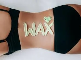 Chest with a tattoo that reads 'WAX' in large letters and a small crown above it, with the person wearing a black top.