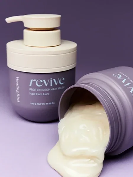 A purple container of revive protein deep hair mask with white lid, alongside another purple container with the lid off and hair mask spilling out.