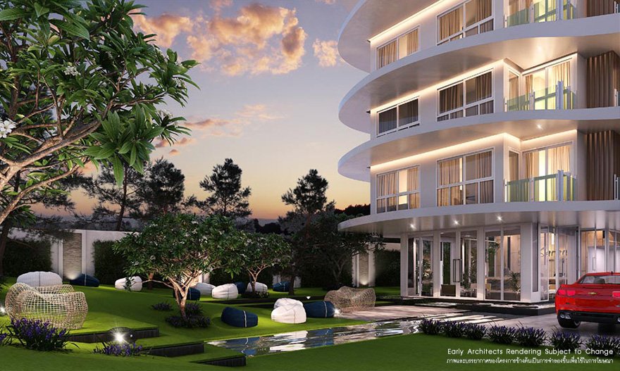Modern multi-story building with curved balconies illuminated at sunset, surrounded by landscaped gardening with trees, lounge seating, and a red car parked outside.
