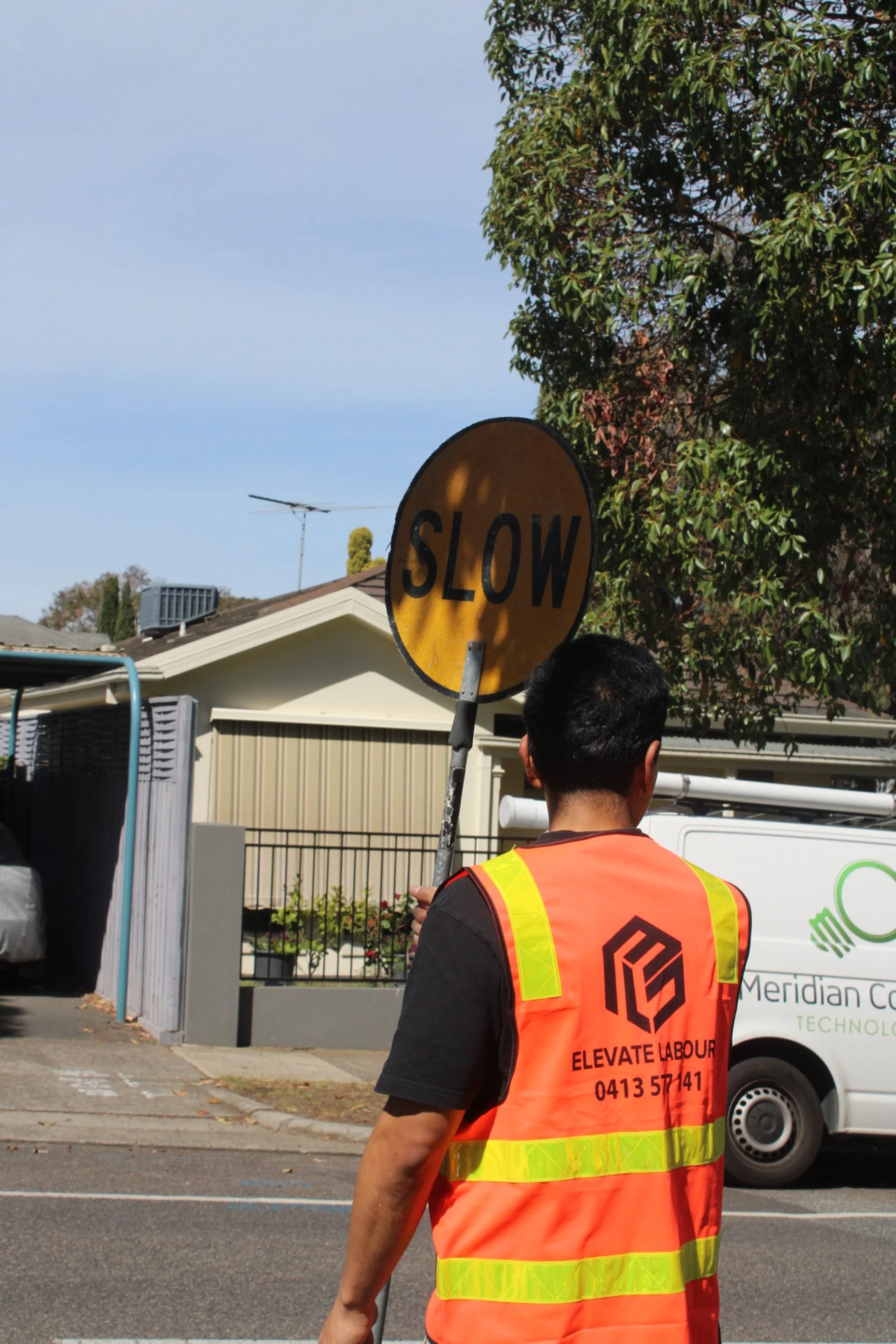 Traffic controller in hi-vis directing vehicles with a stop slow bat at a construction site