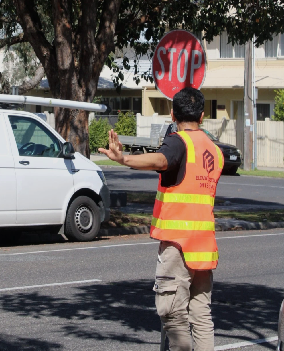 Traffic control officer in hi-vis vest holding stop sign at a construction site