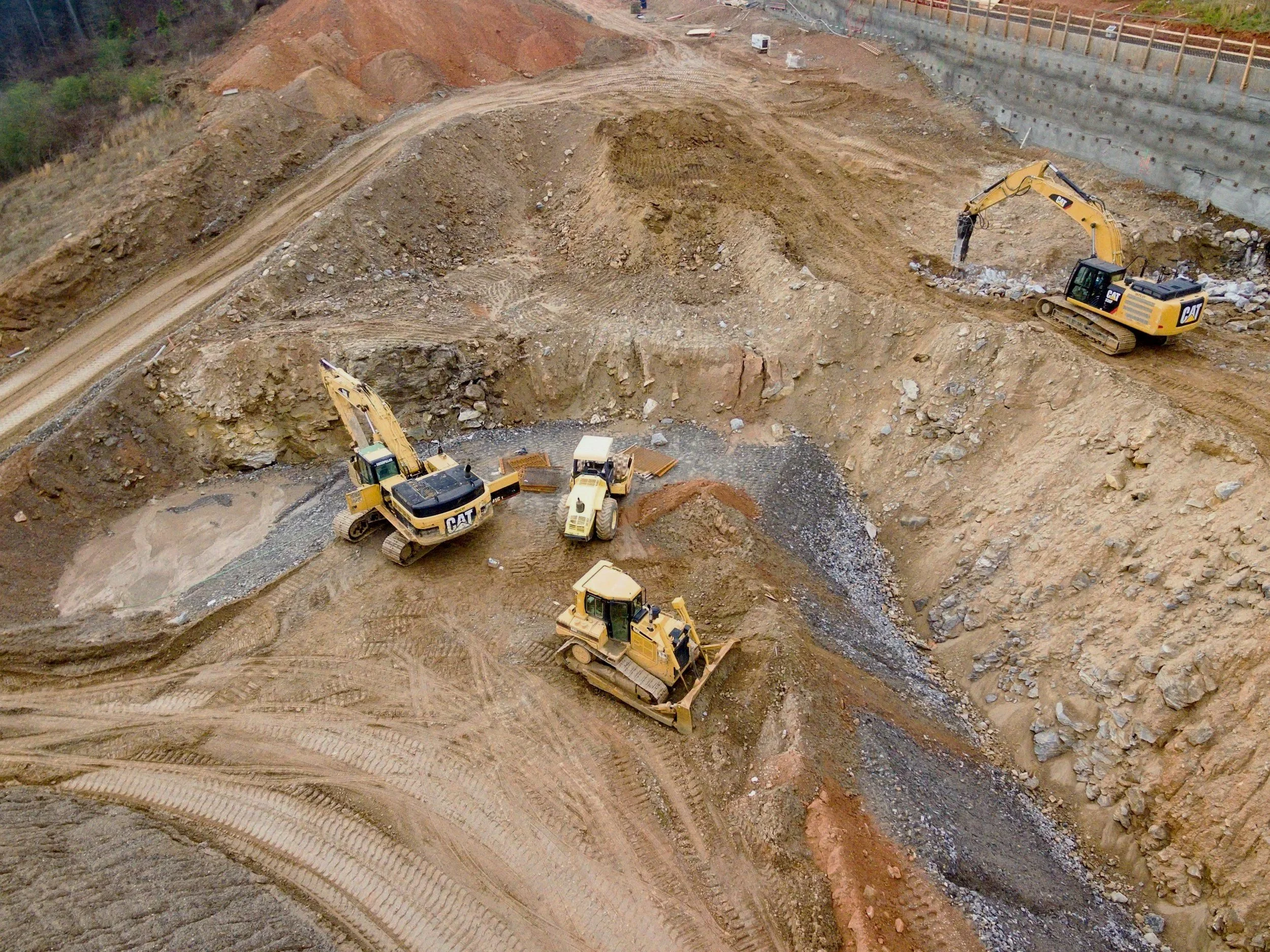 Roller, dozer, and excavator working together on a civil construction site