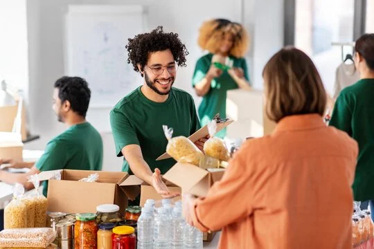 People volunteering at a food drive, handing out boxed goods and water bottles.