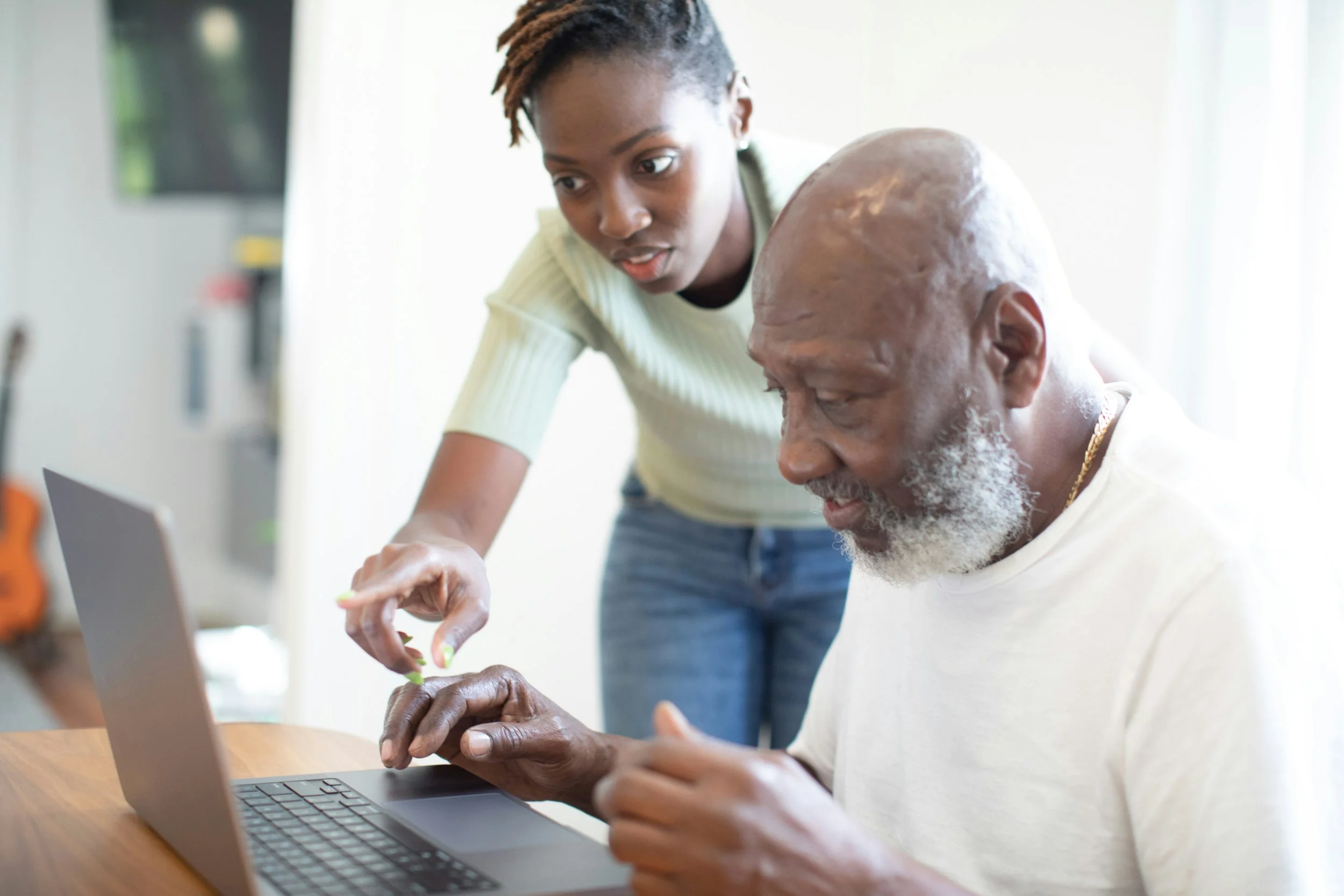 Young woman helping older man with computer