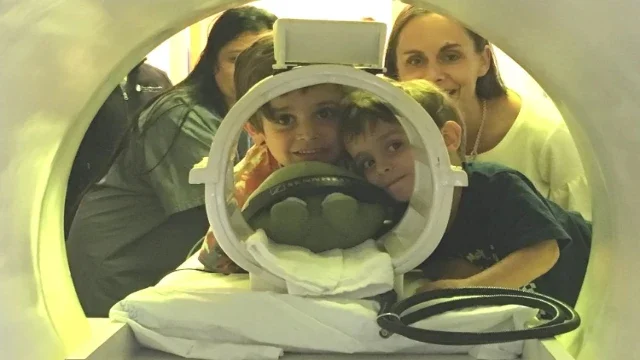 Young boys peeking through MRI machine