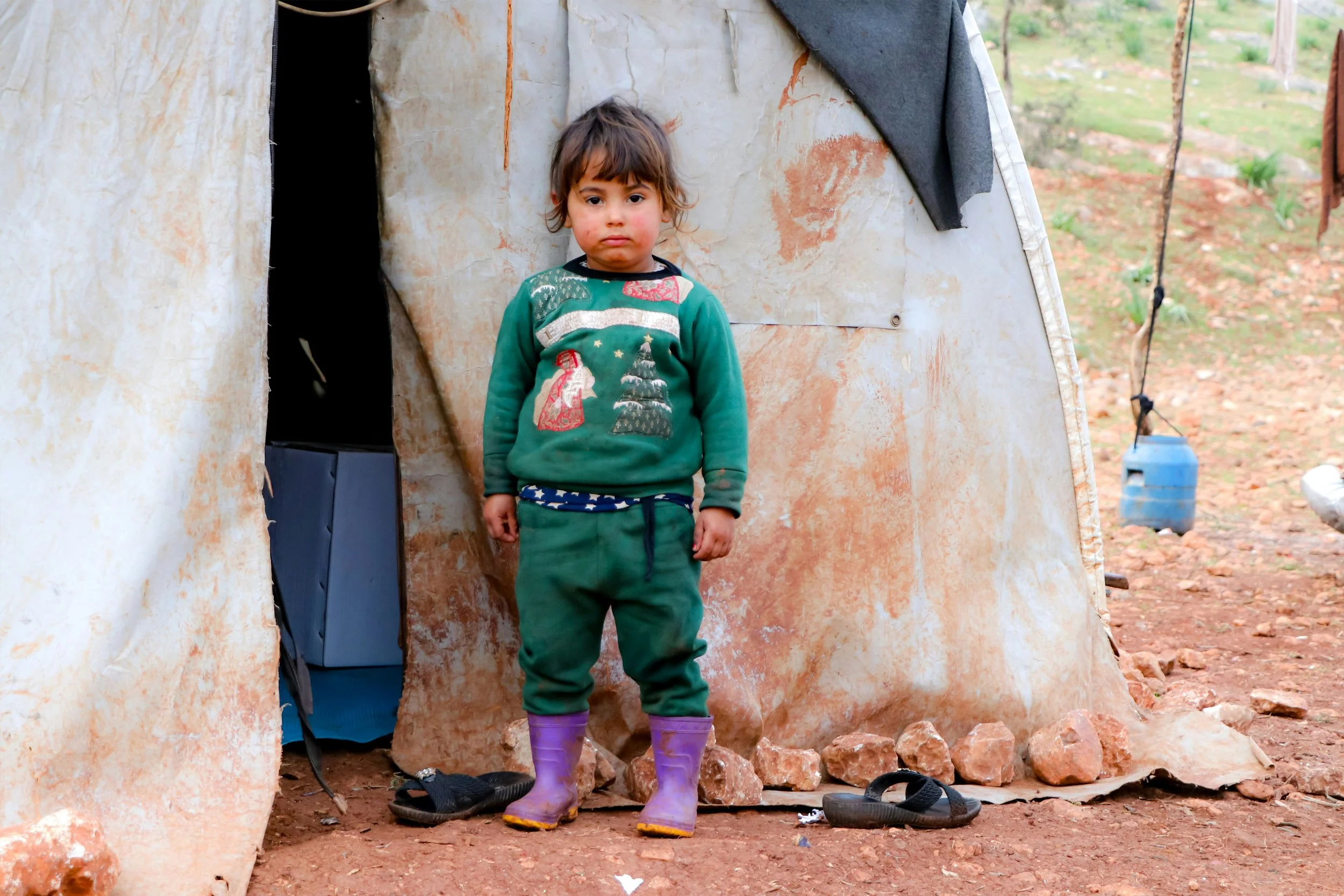 Young girl outside refugee camp tent