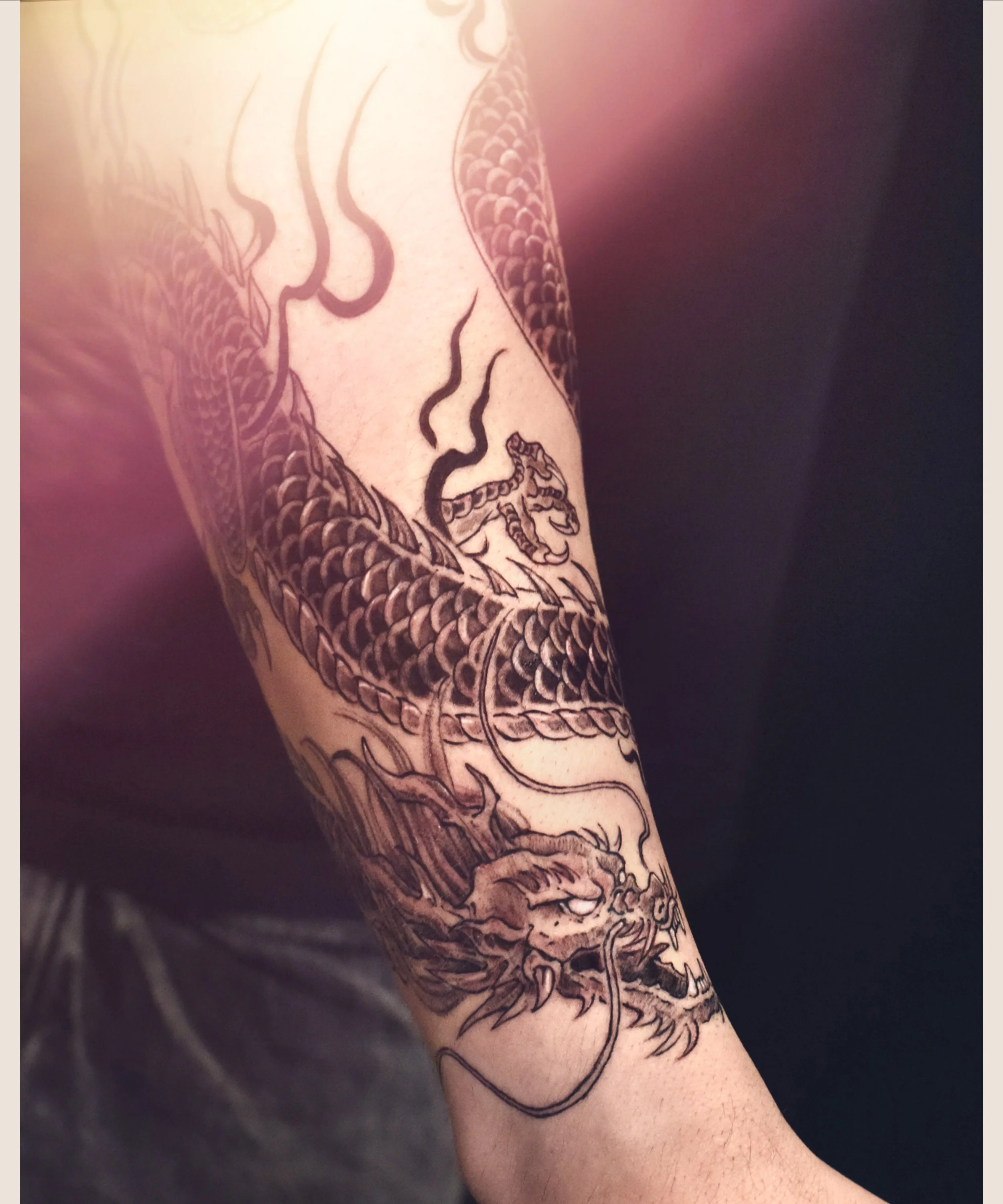 Black Dragon tattoo wrap around forearm with black flame , craft and designed by Bored ink club, located in Los Angeles