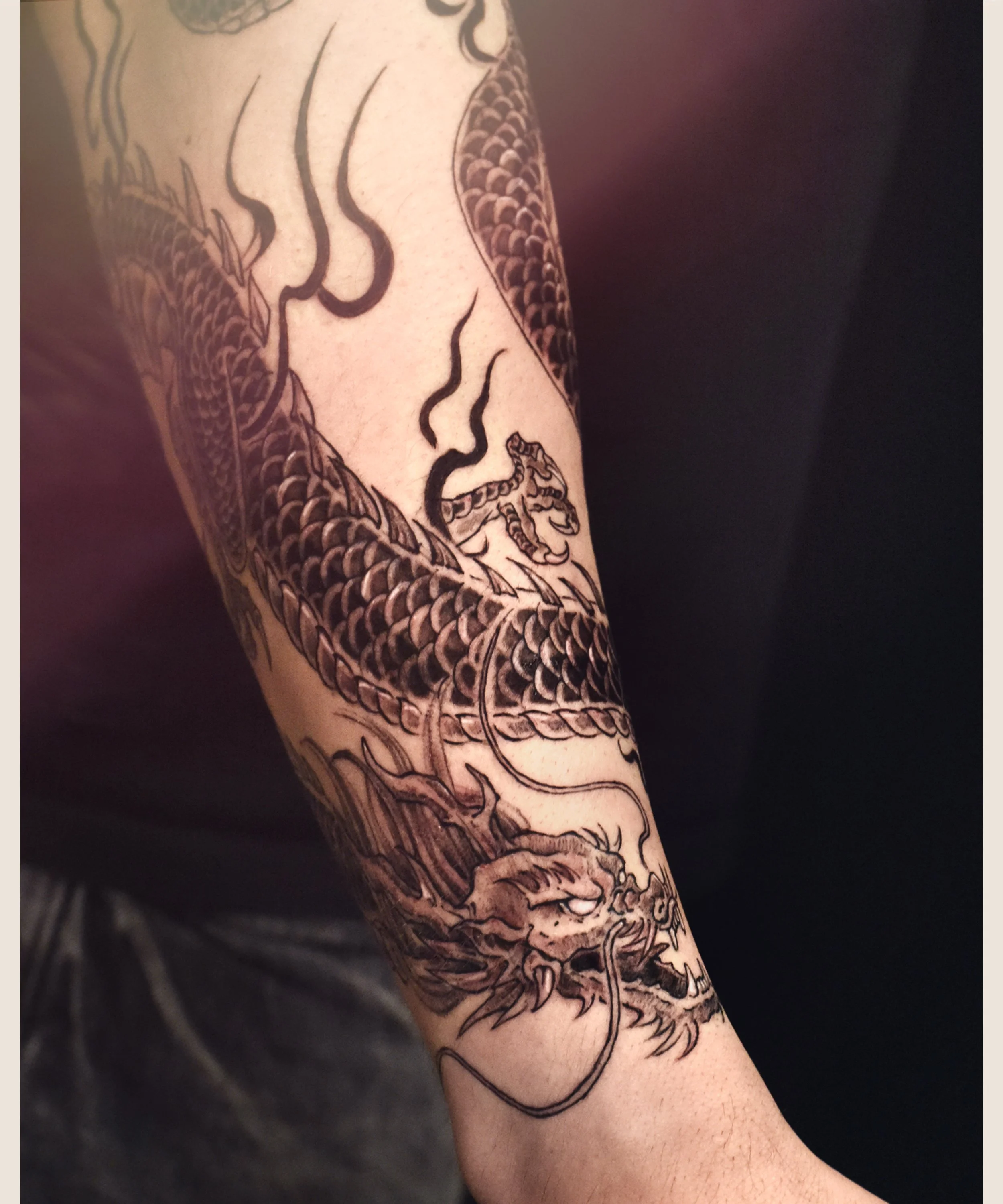 Black Dragon tattoo wrap around forearm with black flame , craft and designed by Bored ink club, located in Los Angeles