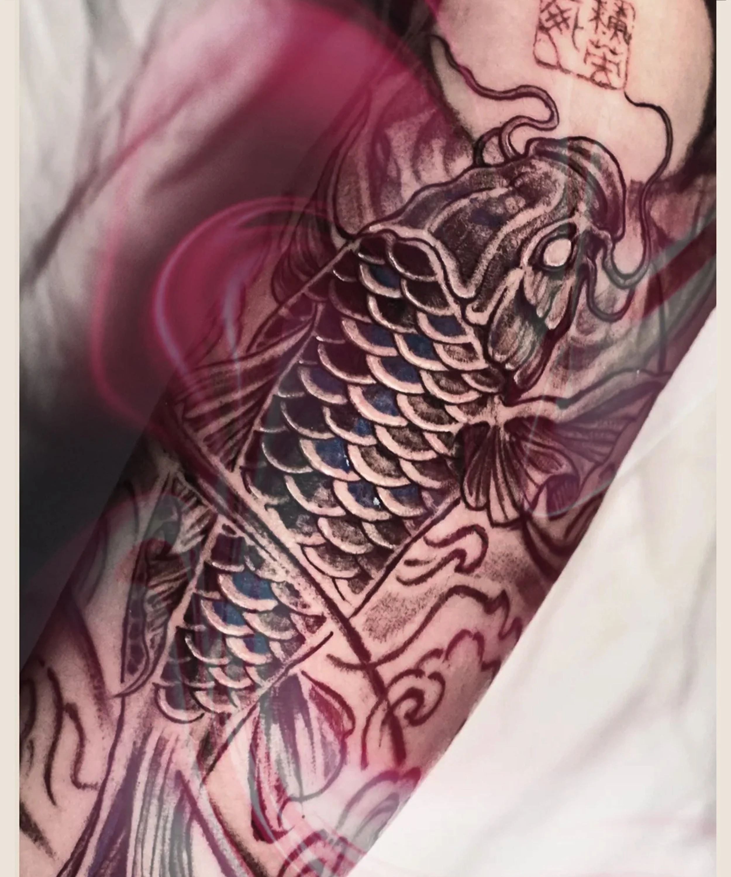 Asian Koi tattoo  swimming up along the arm with wave elements, crafted and designed by Bored ink club, located in Los Angeles
