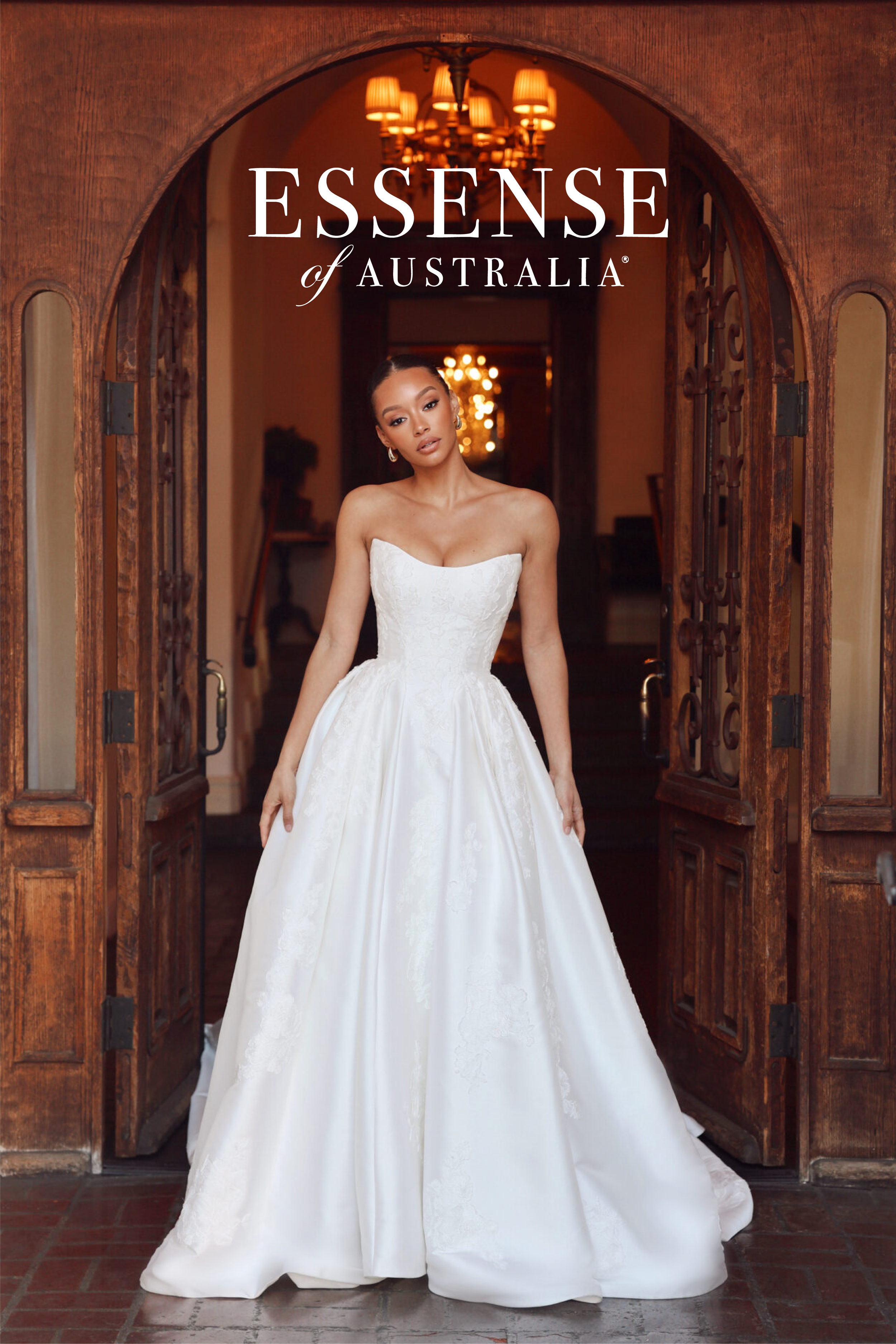 A woman wearing a white wedding gown standing in a doorway with wooden framing, with a chandelier visible in the background. The text 'Essence of Australia' is overlaid at the top.