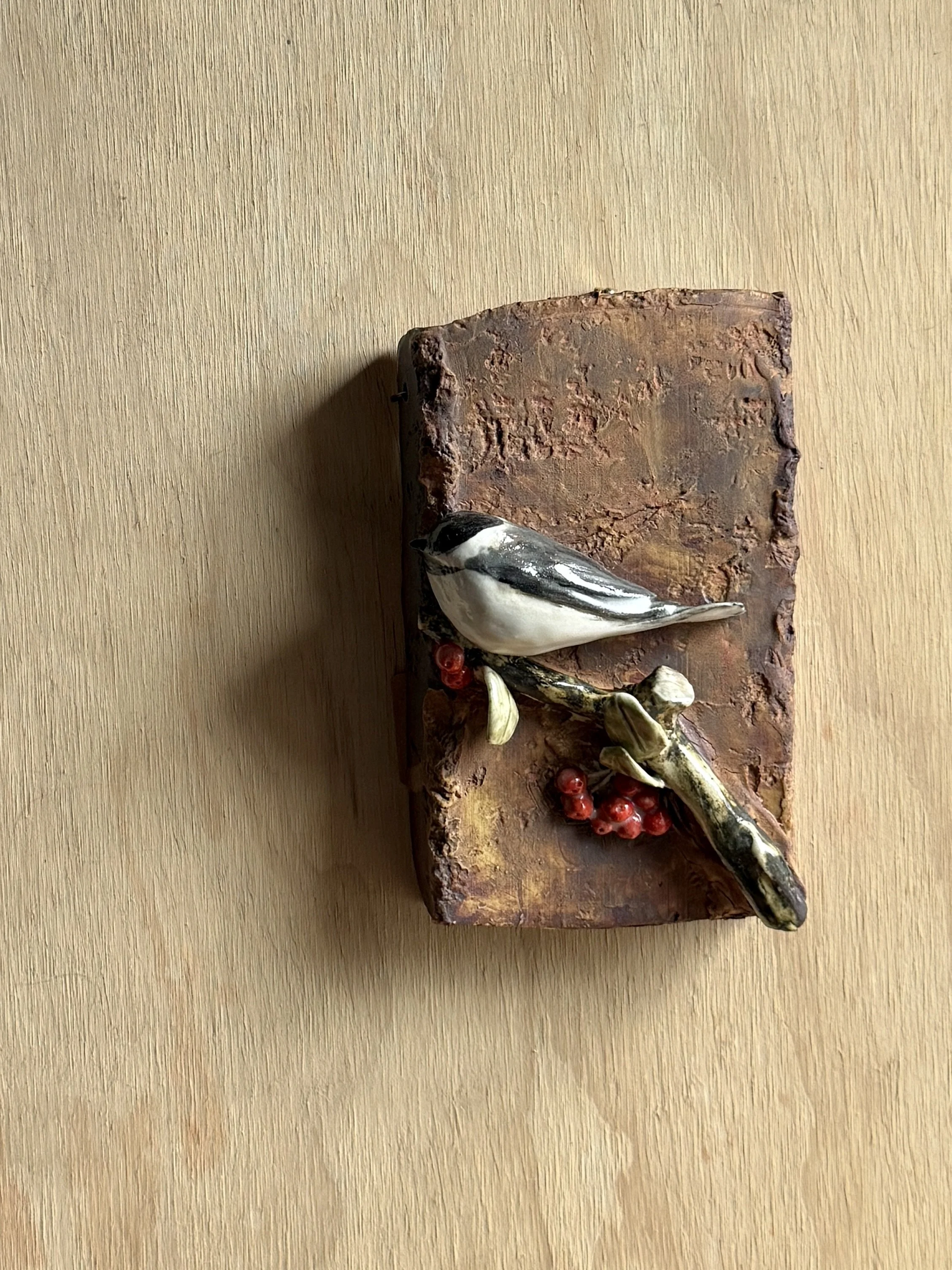 Black-capped chickadee with red huckleberry on wall plaque