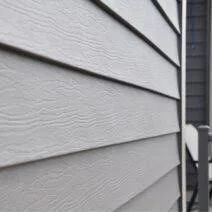 Close-up of a house's exterior siding with horizontal beige vinyl panels.