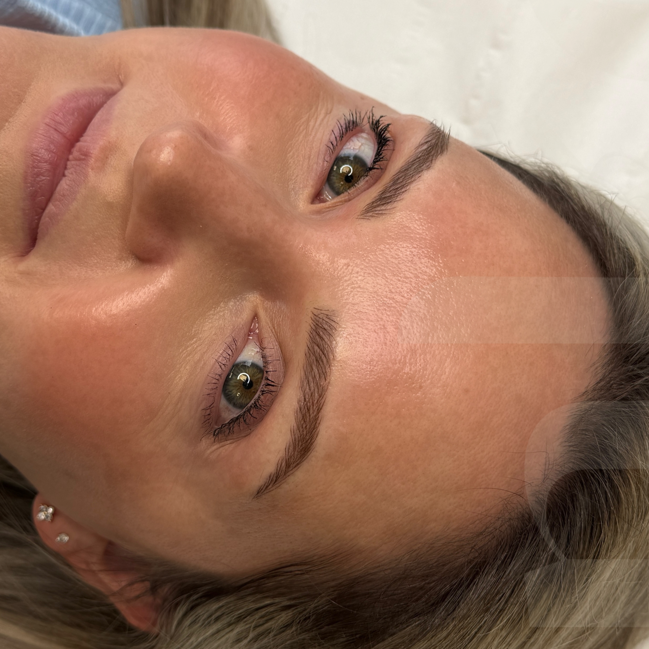 Close-up of a woman's face lying on her back, showing her forehead, eyebrows, eyes, and part of her nose and cheeks.