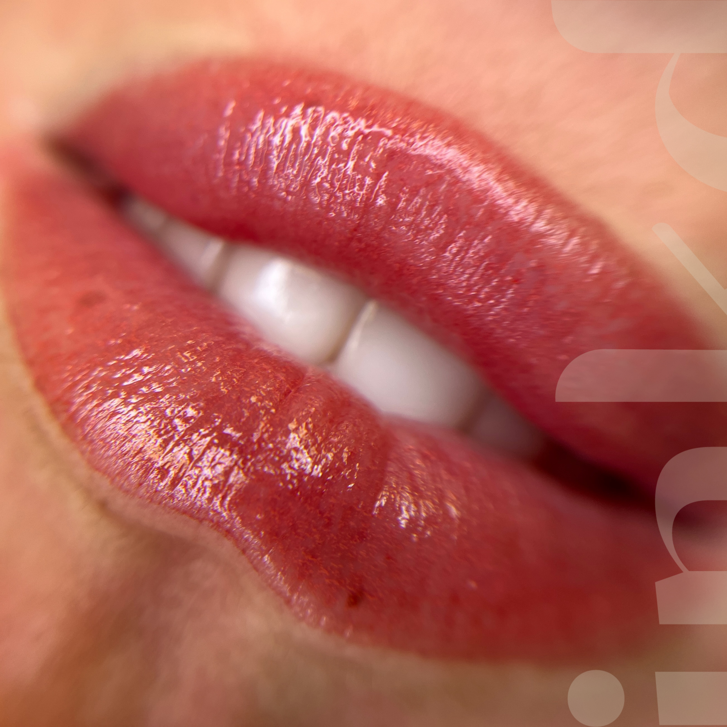 Close-up of a person's lips with glossy red lipstick, slightly parted to reveal white teeth.