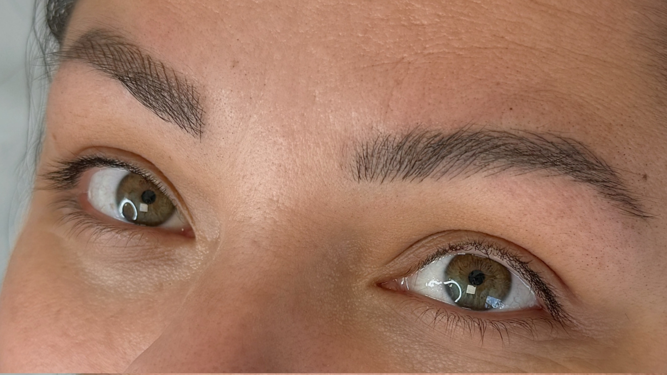 Close-up of a person's face showing brown eyes with detailed eyebrows and skin texture.