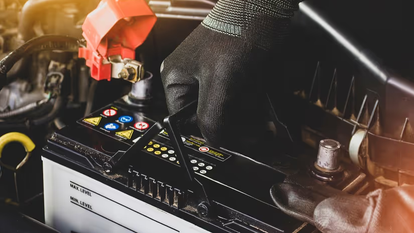Person in black gloves using a diagnostic scanner to check a car engine.