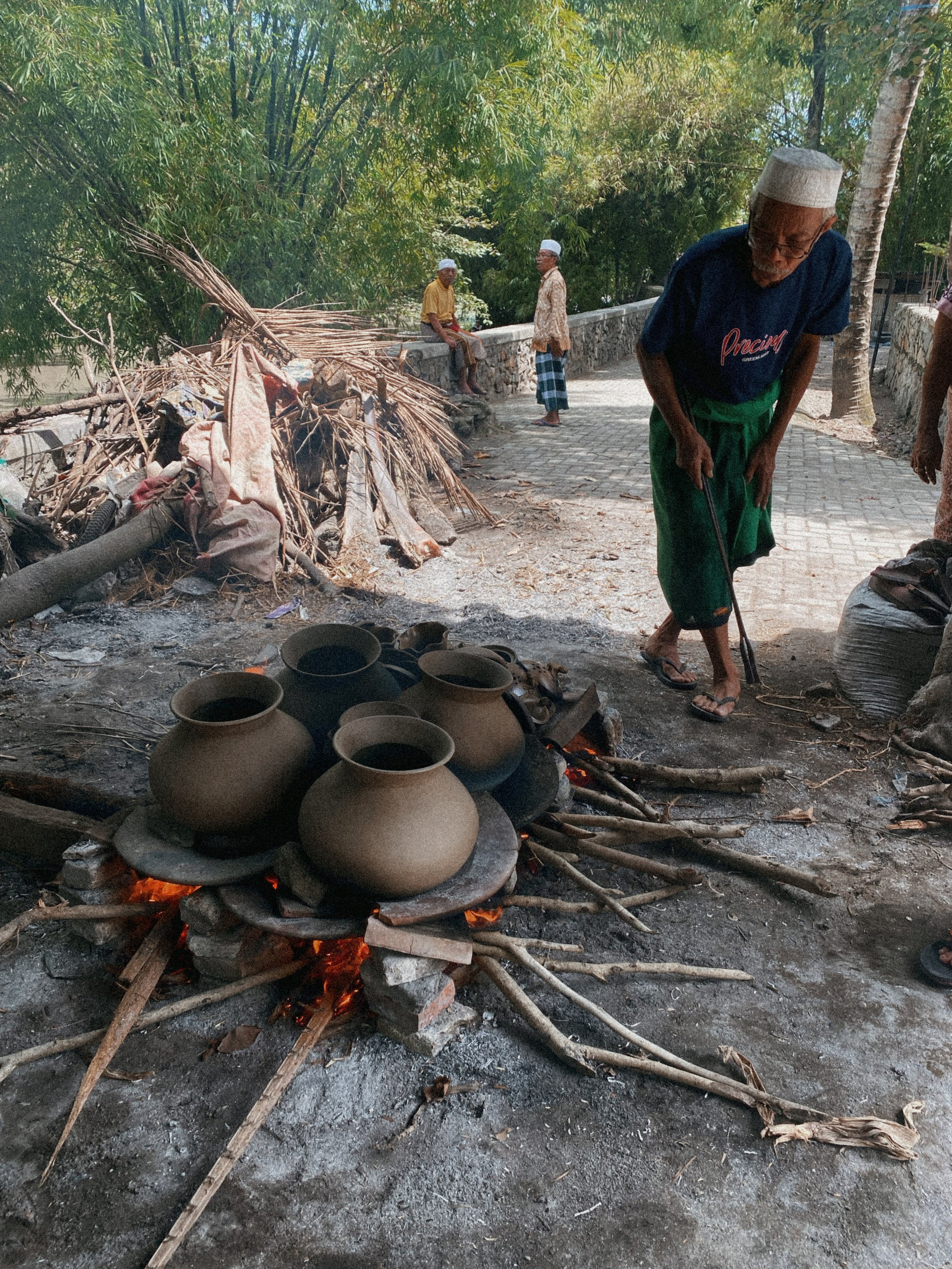 Bapak Aji, a master potter tending to clay pottery being fired, in Lombok Indonesia. 