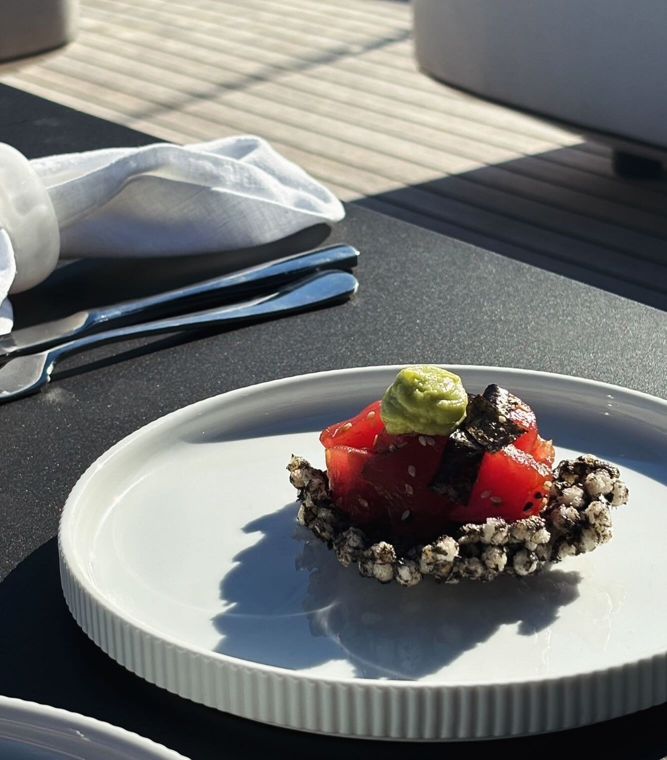 Entree is served, Sesame tuna, squid ink tapioca cracker, avocado wasabi.