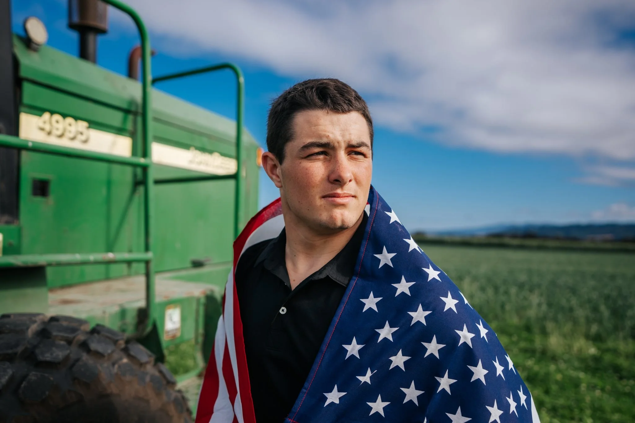 Tanner Pidgeon in a cornfield holding the American flag during his Ferndale High School senior portrait session by Tex Kelly Productions