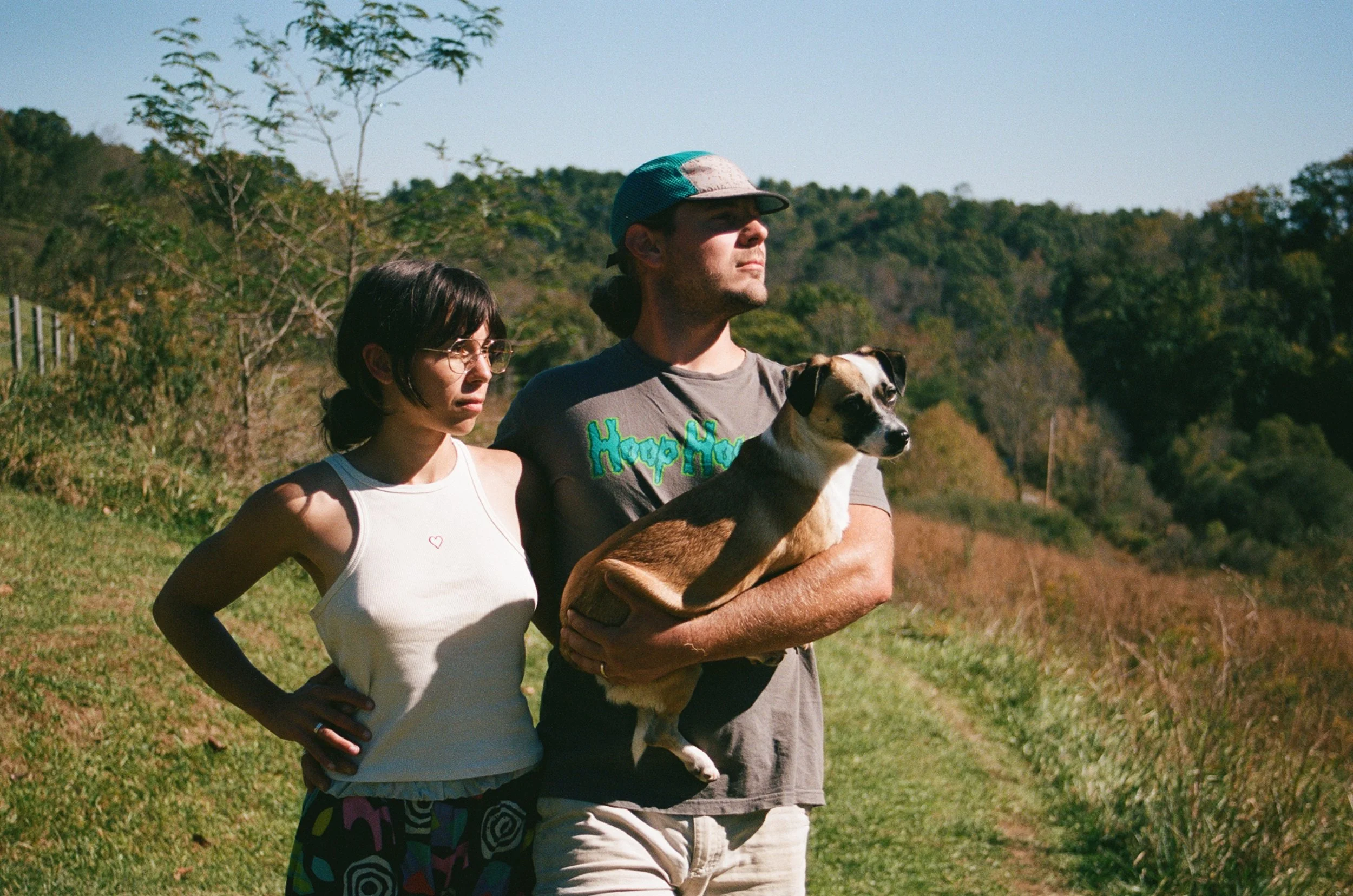 A man, a woman, and their dog standing on their farm