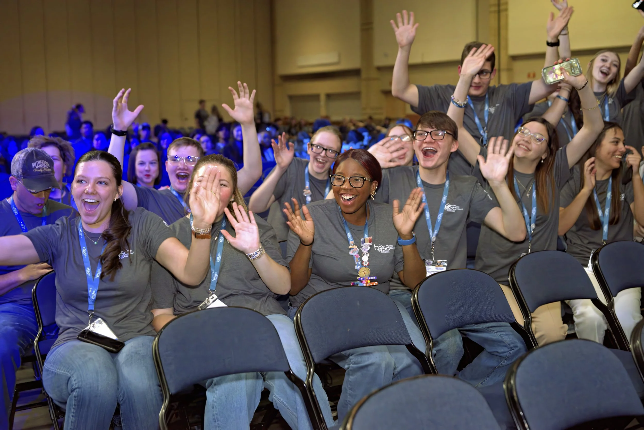 A group of HOSA members cheering with their hands held up in the air during an energetic general session.