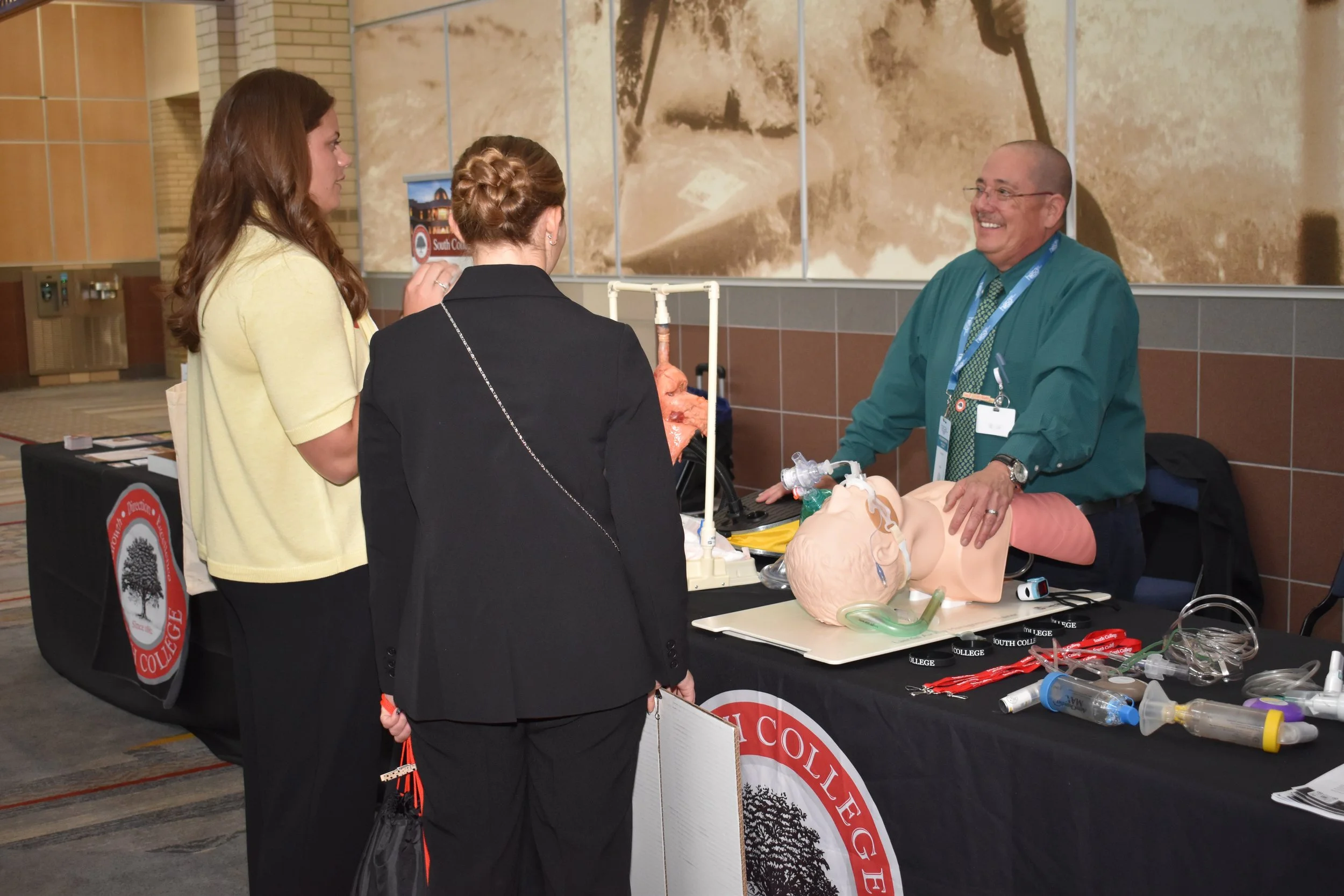 Two students interact with an exhibitor.