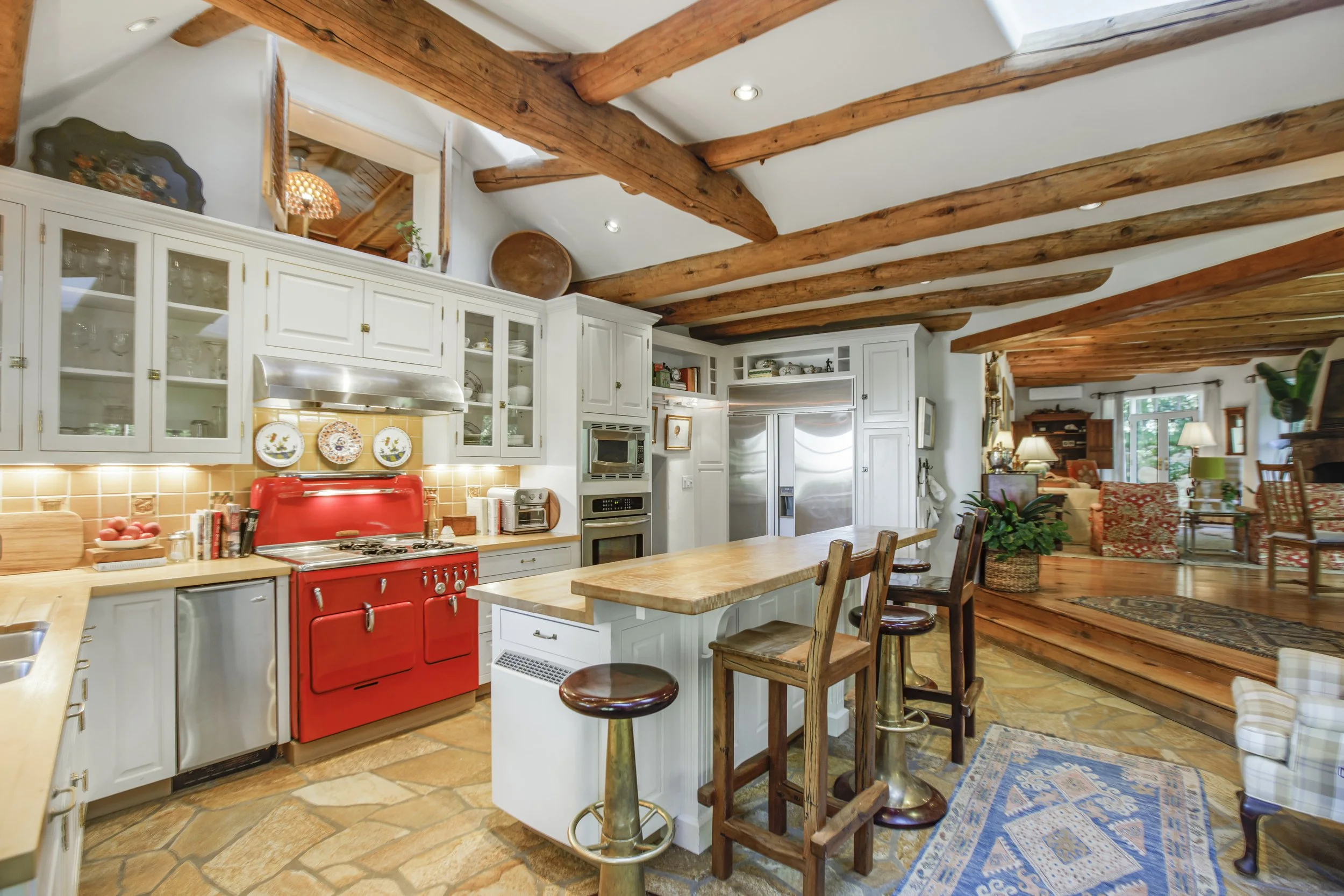 Chef's kitchen with vintage red Chambers stove, exposed wood beams, and white cabinetry at Streamside El Salto