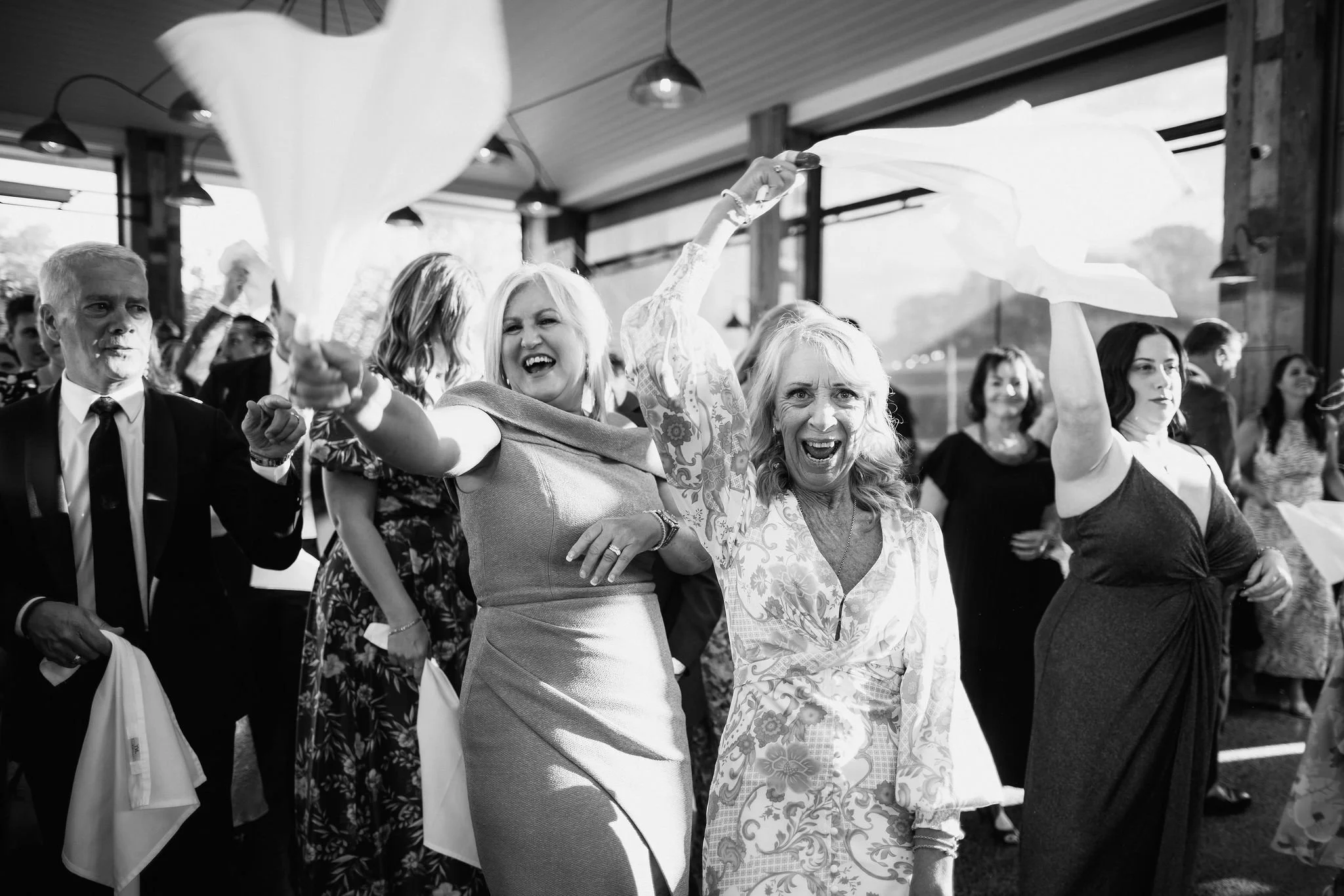 People celebrating at a party, waving napkins in the air and smiling.