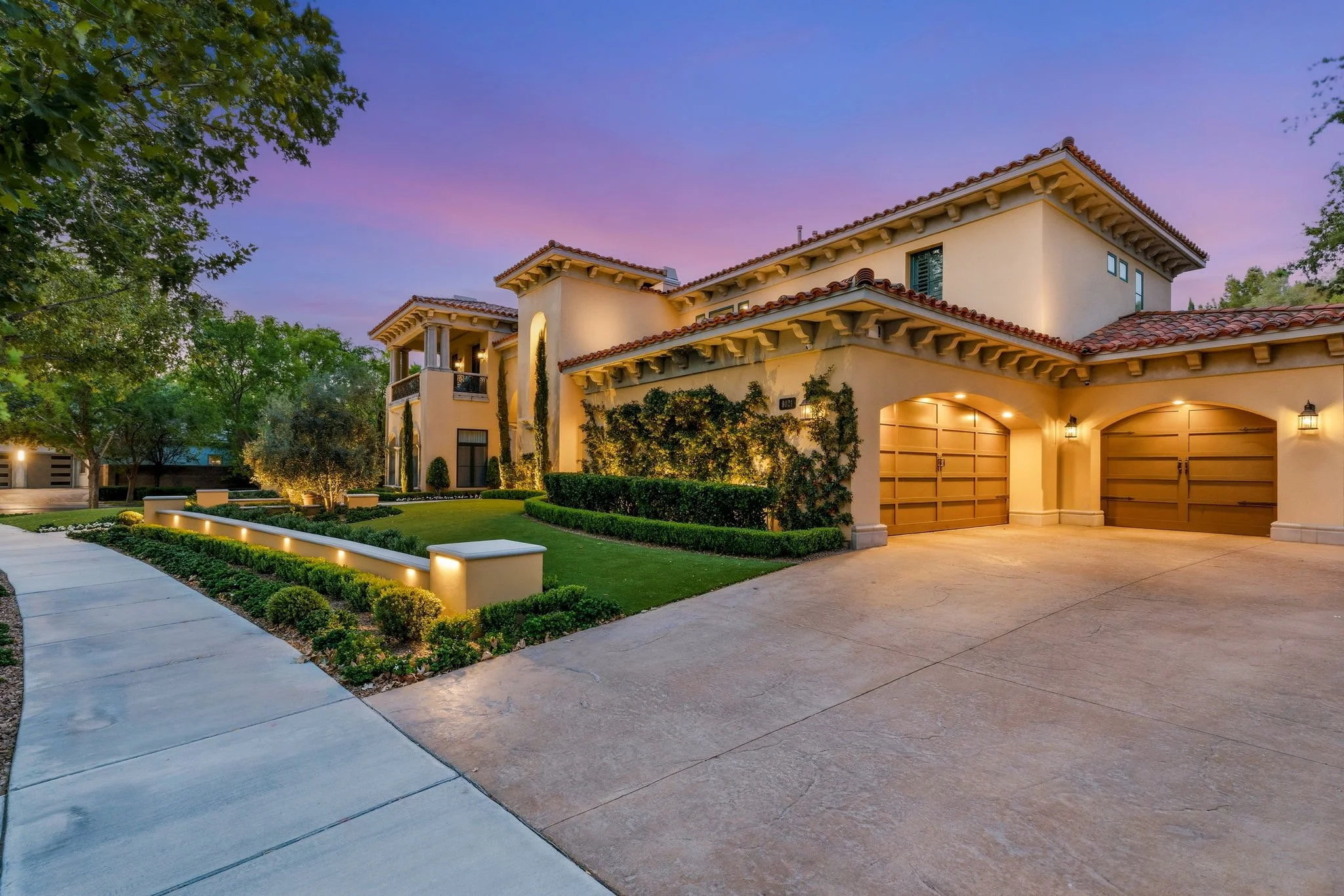 Luxury front yard landscape design with custom paver driveway, manicured lawn, and warm exterior lighting in Eagle Hills, Las Vegas.