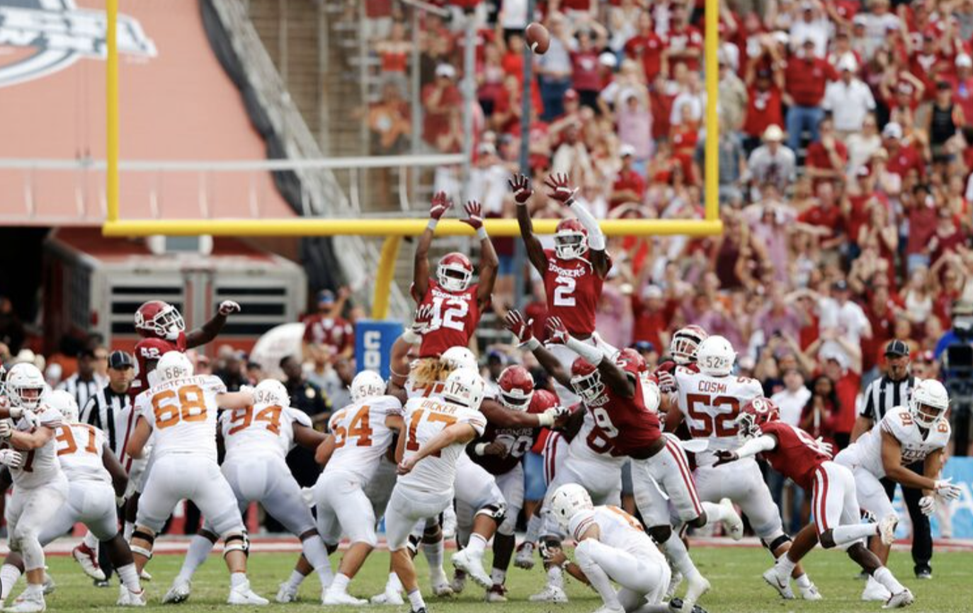 American football game with players leaping to catch the ball near the goal post, crowd watching in the stadium.