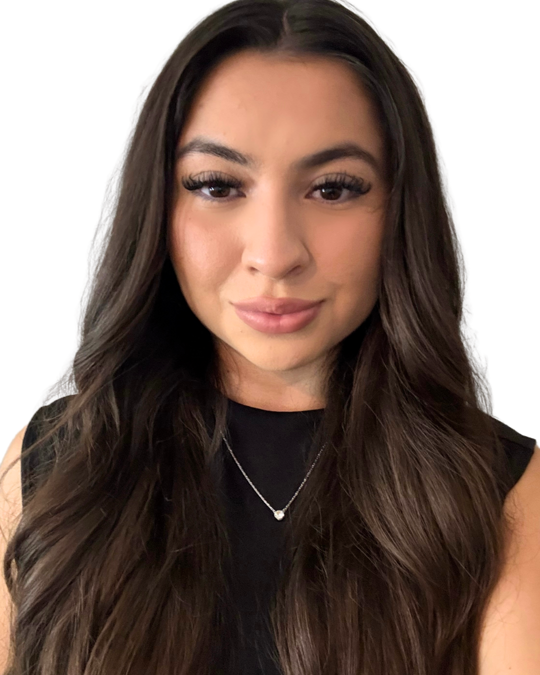 Close-up of a young woman with long, dark brown wavy hair, wearing a black sleeveless top and a silver necklace with a small pendant, smiling softly against a white background.