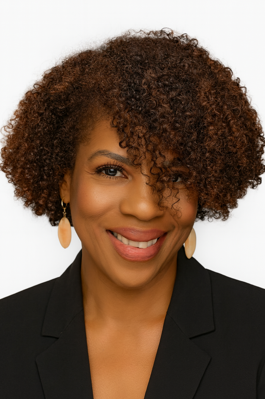 Close-up portrait of a smiling woman with curly brown hair, wearing gold earrings and a black blazer, against a white background.