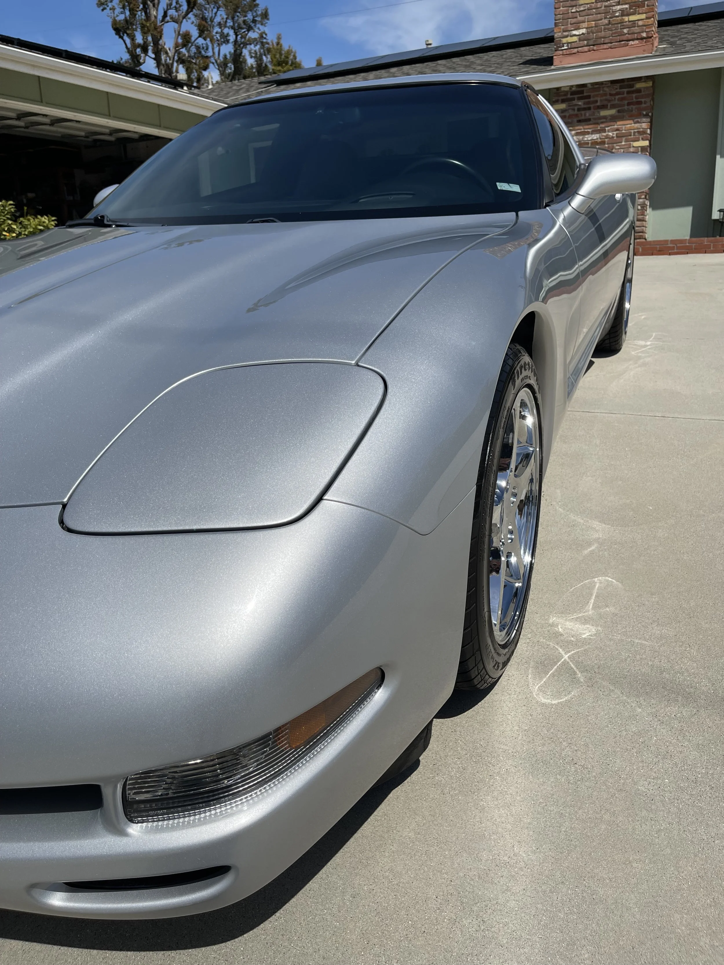 Silver sports car parked on driveway outside house.