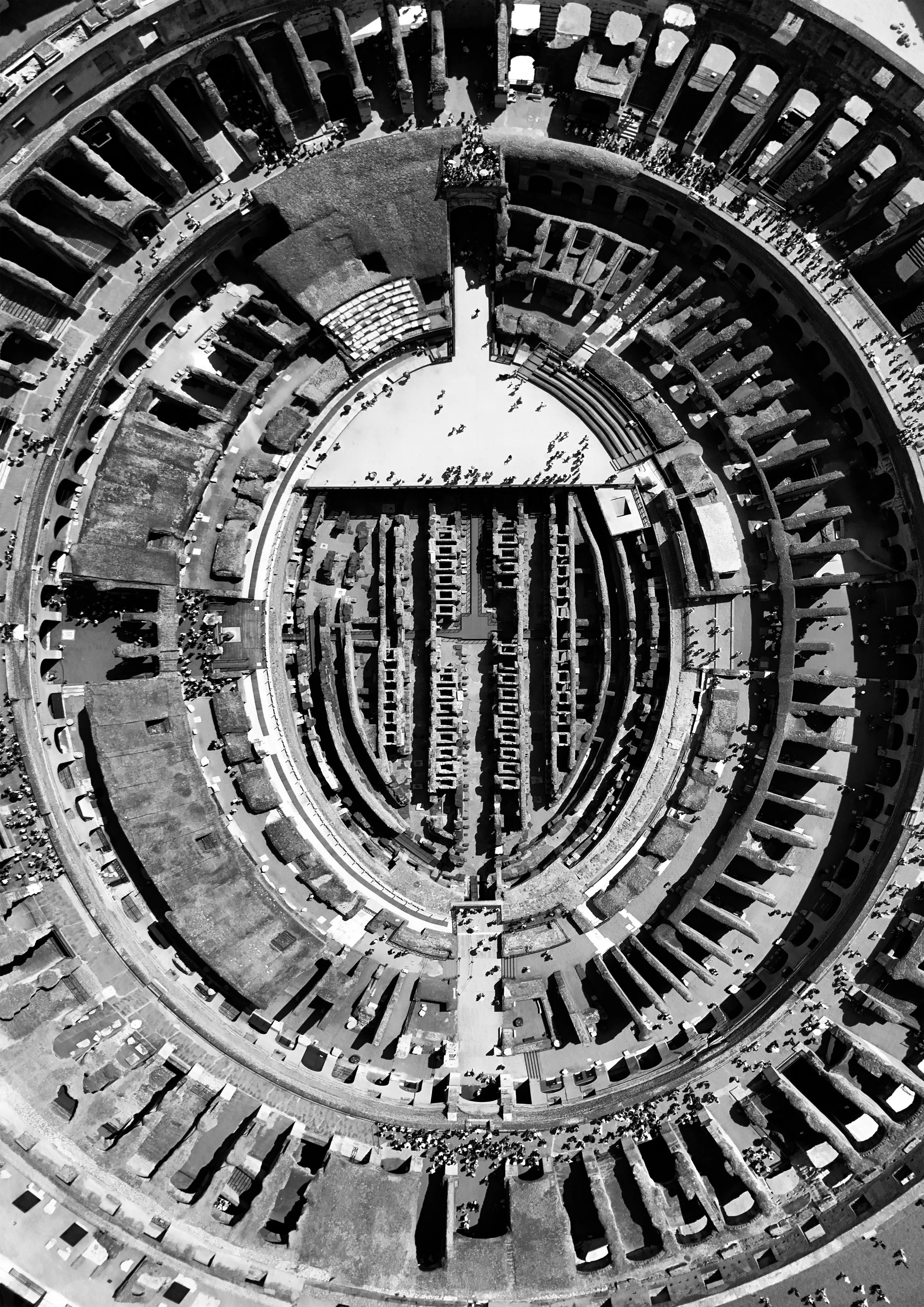 Aerial view of the Colosseum in Rome, Italy, looking down into an open arena surrounded by tiered seating and ancient arches, with people walking around.