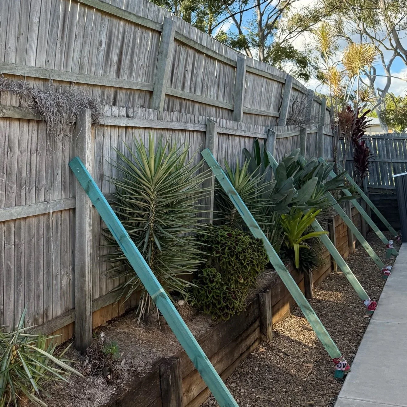 An emergency make safe after a big storm. A fence is being supported with wooden slats to prevent it from falling over.
