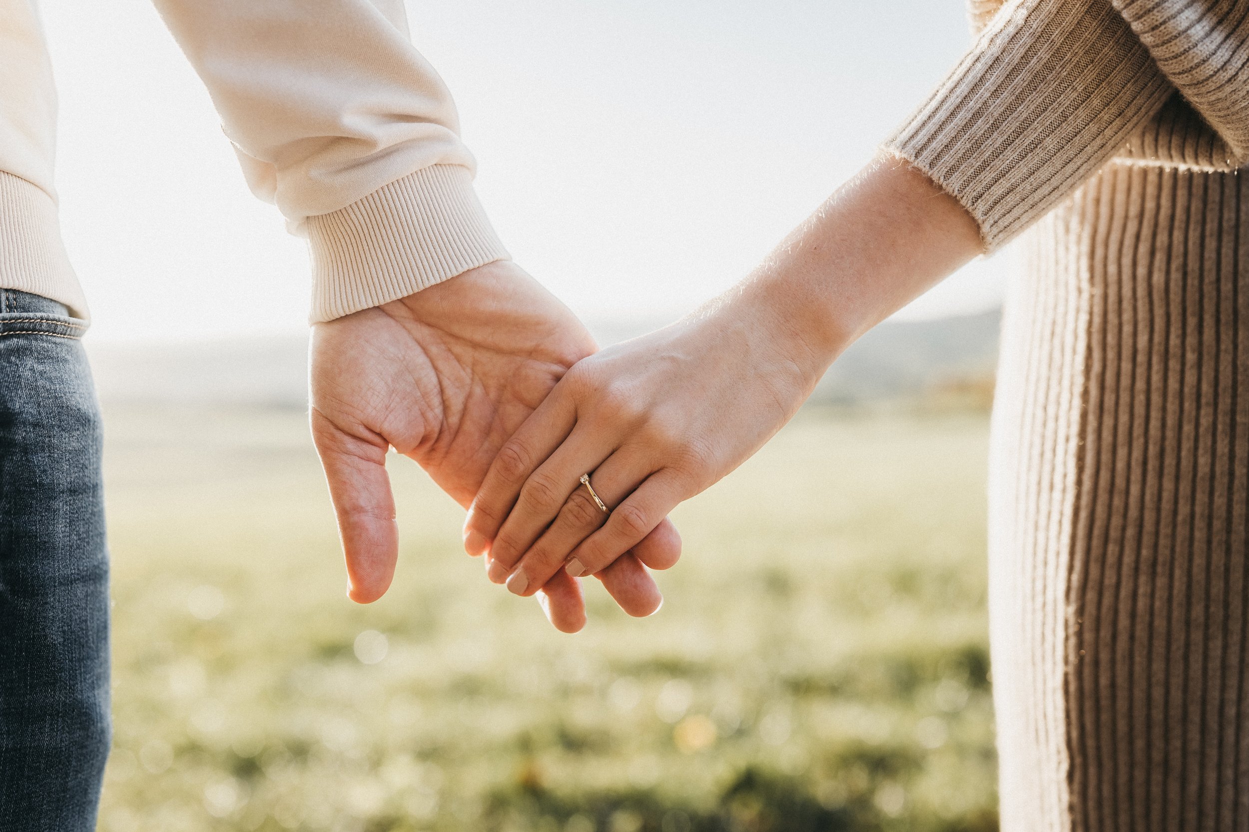 Ein Paar hält bei Sonnenlicht Händchen in einer natürlichen Umgebung.