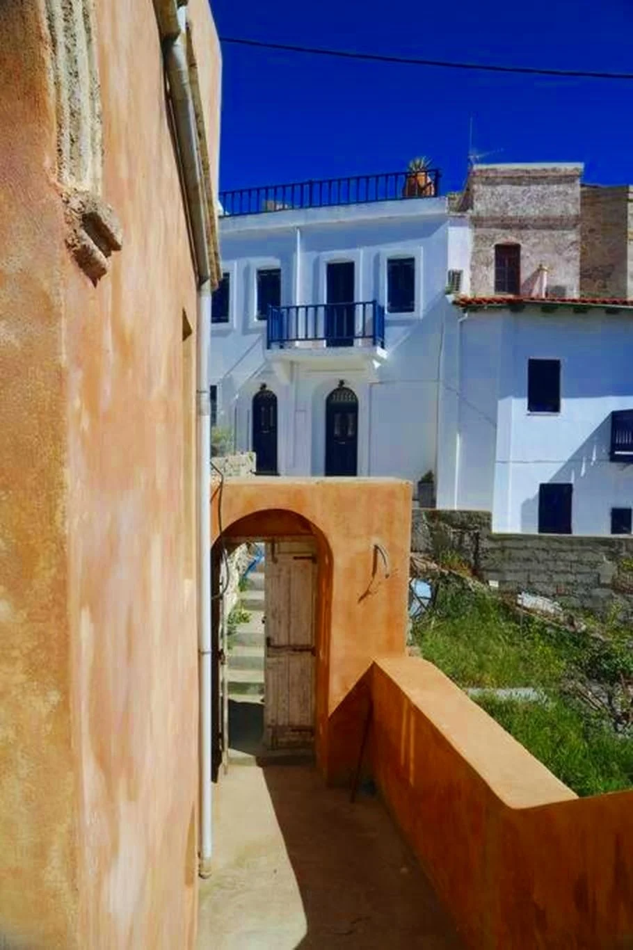 Narrow alleyway between colorful buildings with blue sky overhead.