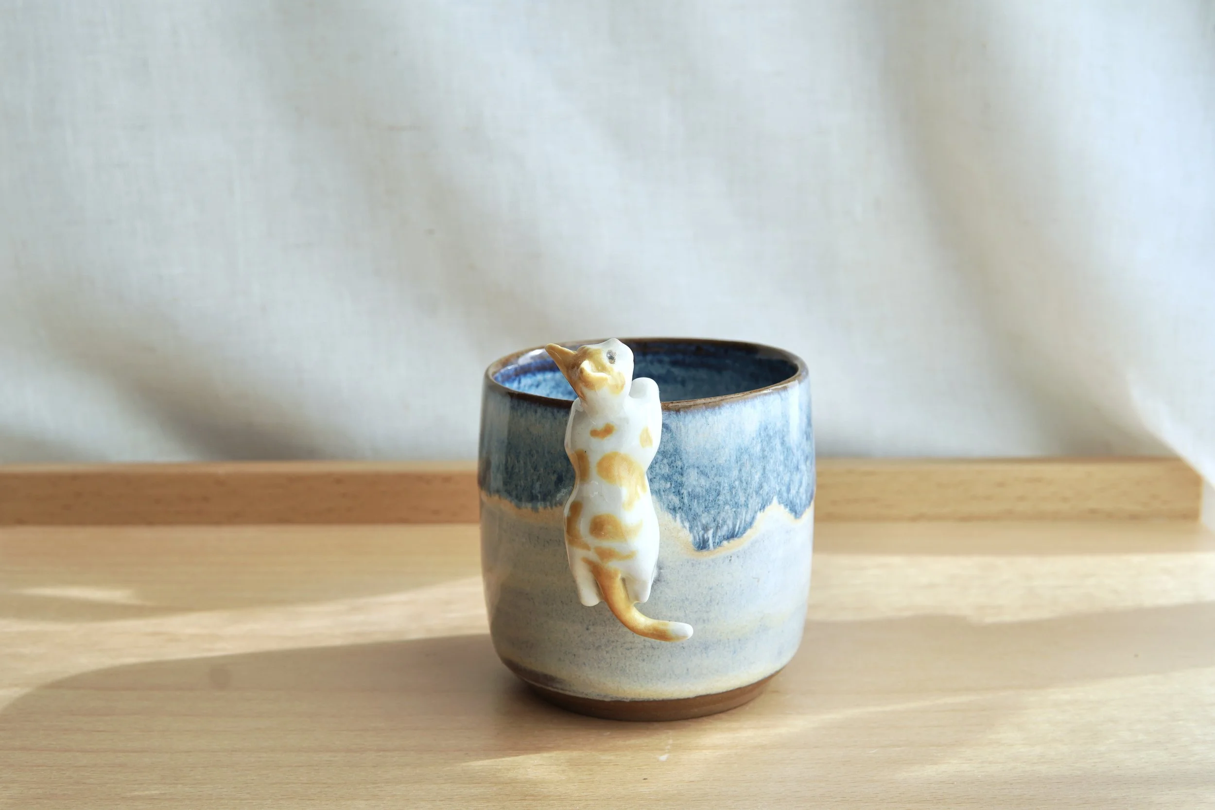 Cat hanging on mug