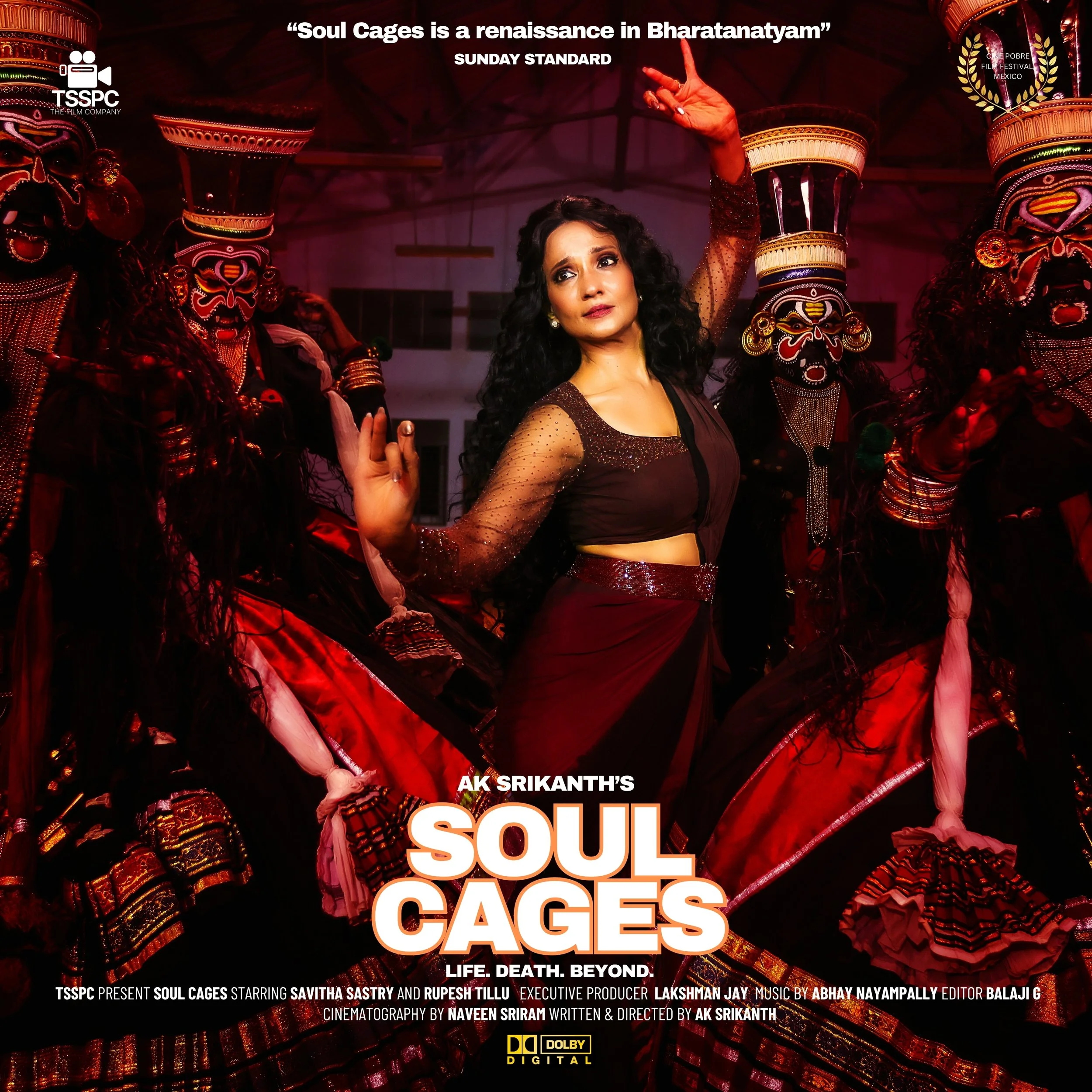 A woman with dark curly hair and a thoughtful expression looking upward, wearing a red and gold beaded dress, standing next to a traditional Balinese Barong mask with intricate red, black, and white designs and large, expressive eyes.