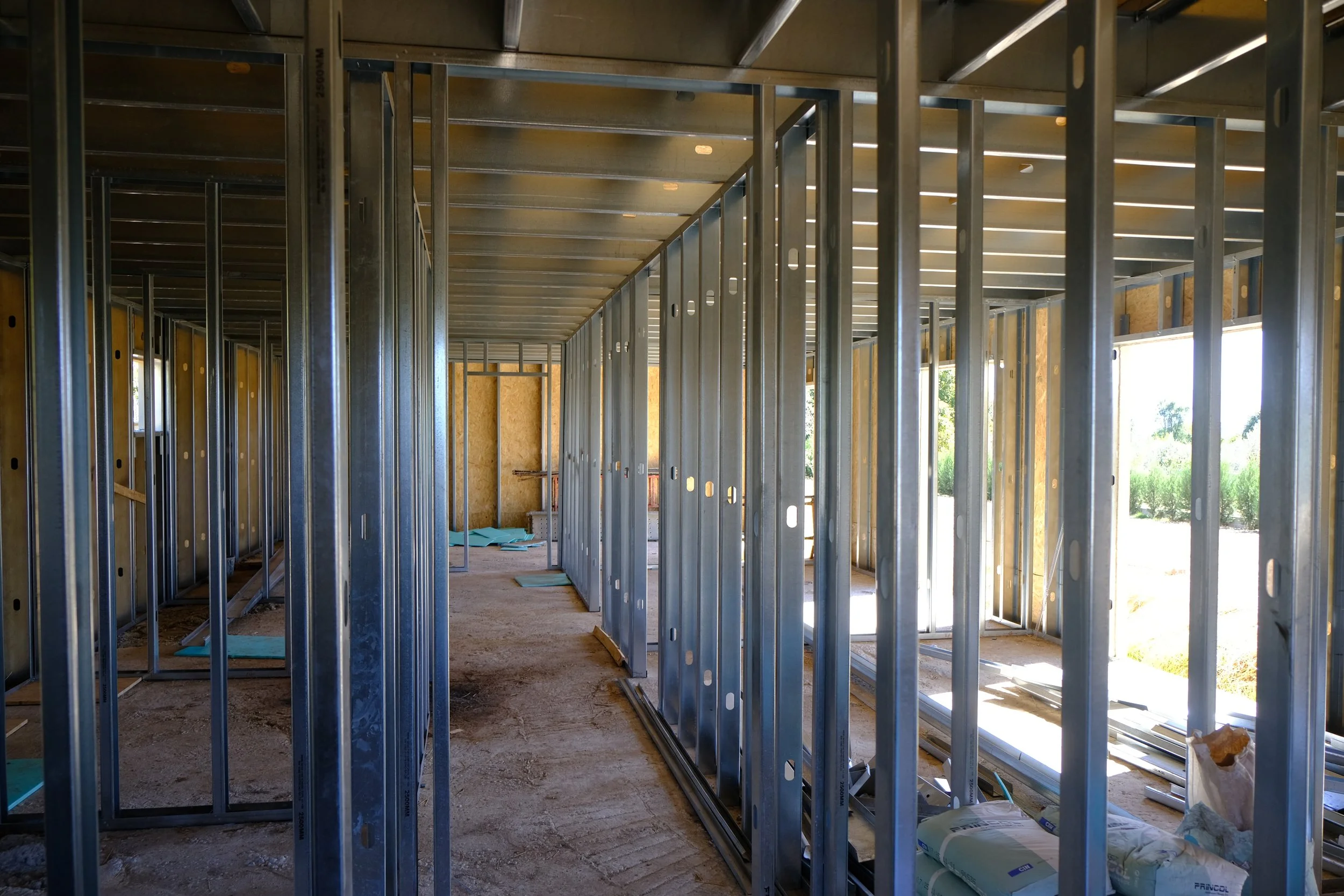 Minimalist modern interior with large window, staircase, mirror, and red cloth on bench.