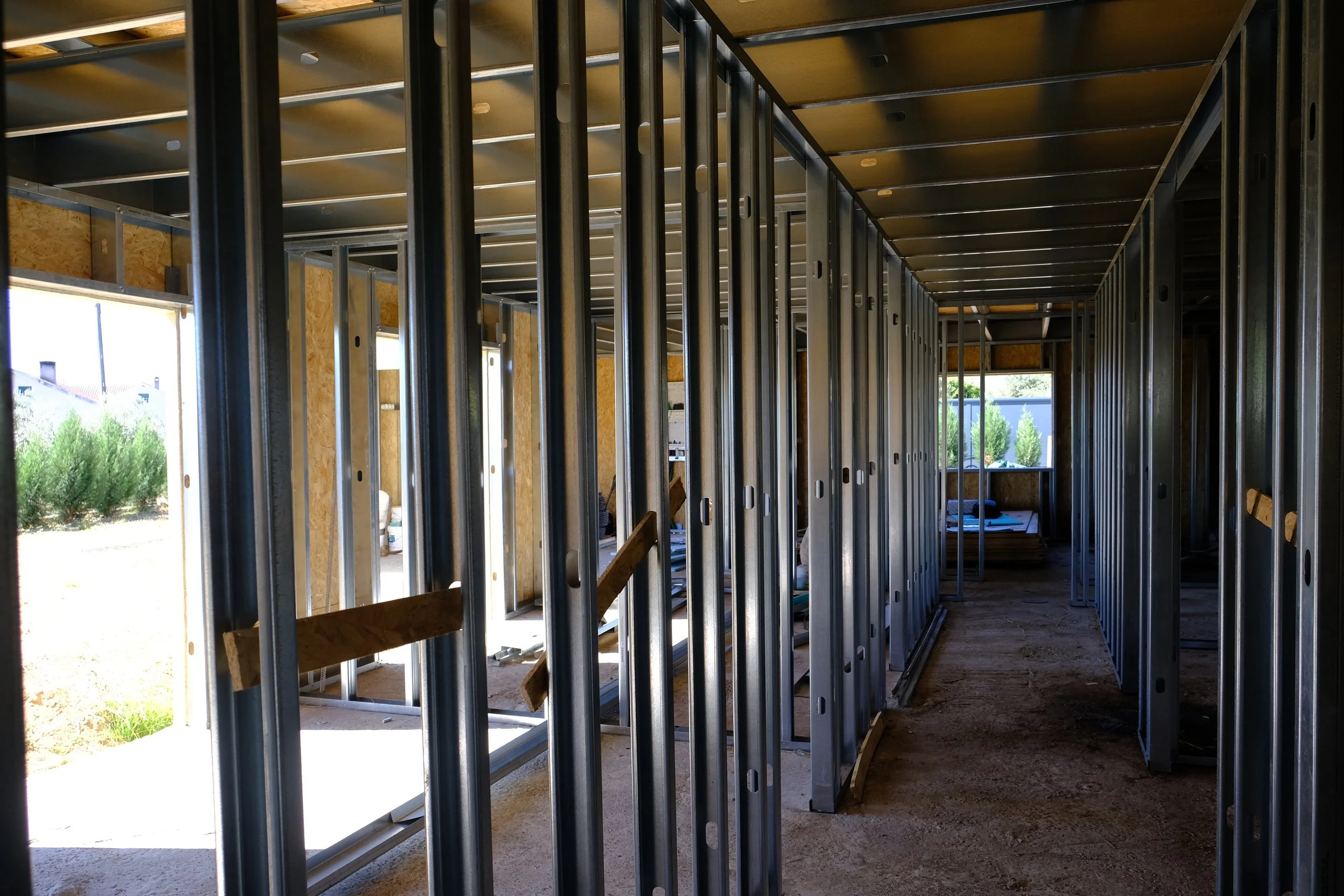 Minimalist interior with large window, staircase, and simple furniture, illuminated by soft natural light.
