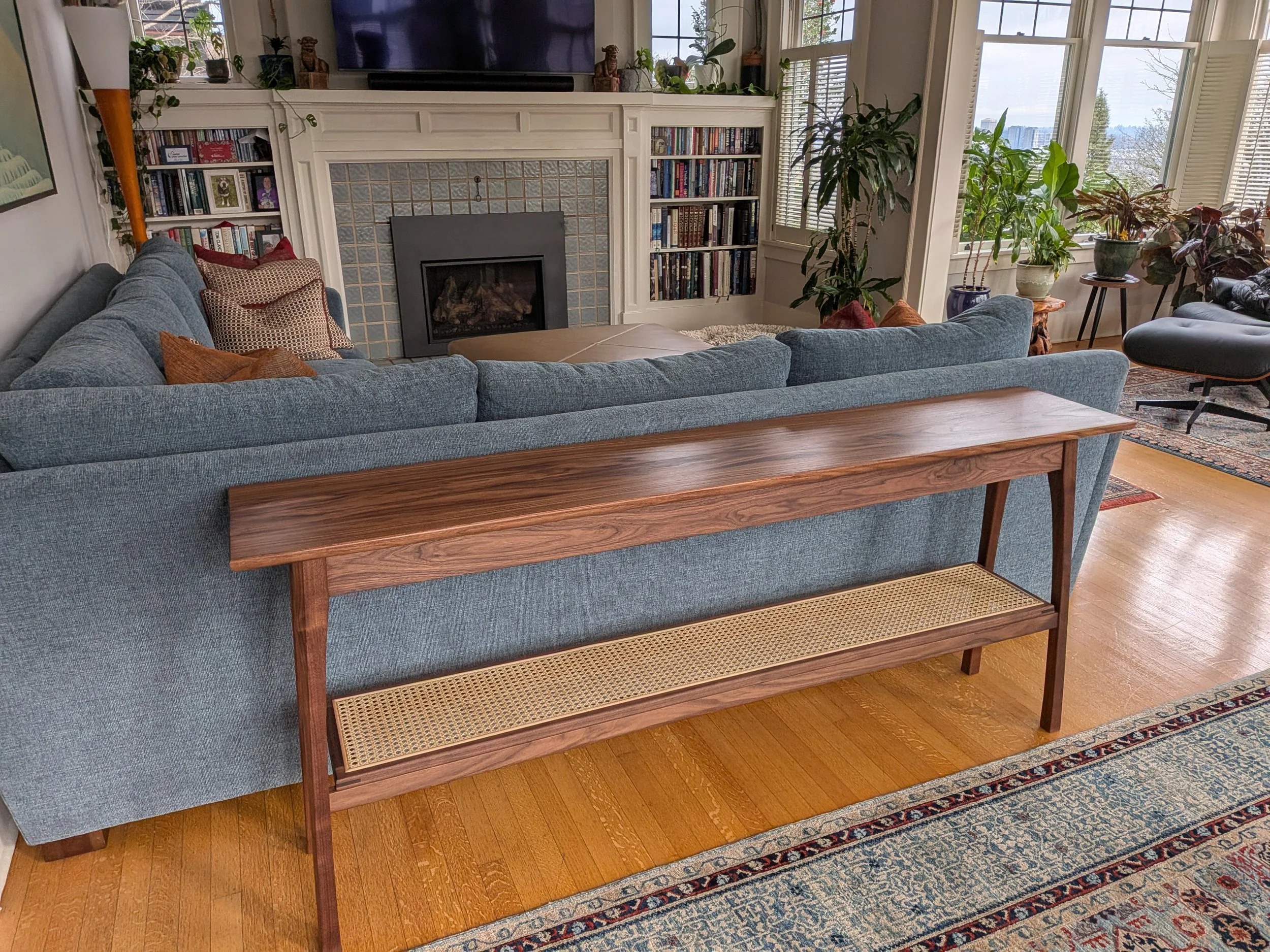 Walnut sofa table with cane shelf behind sectional sofa, Pacific Northwest living room