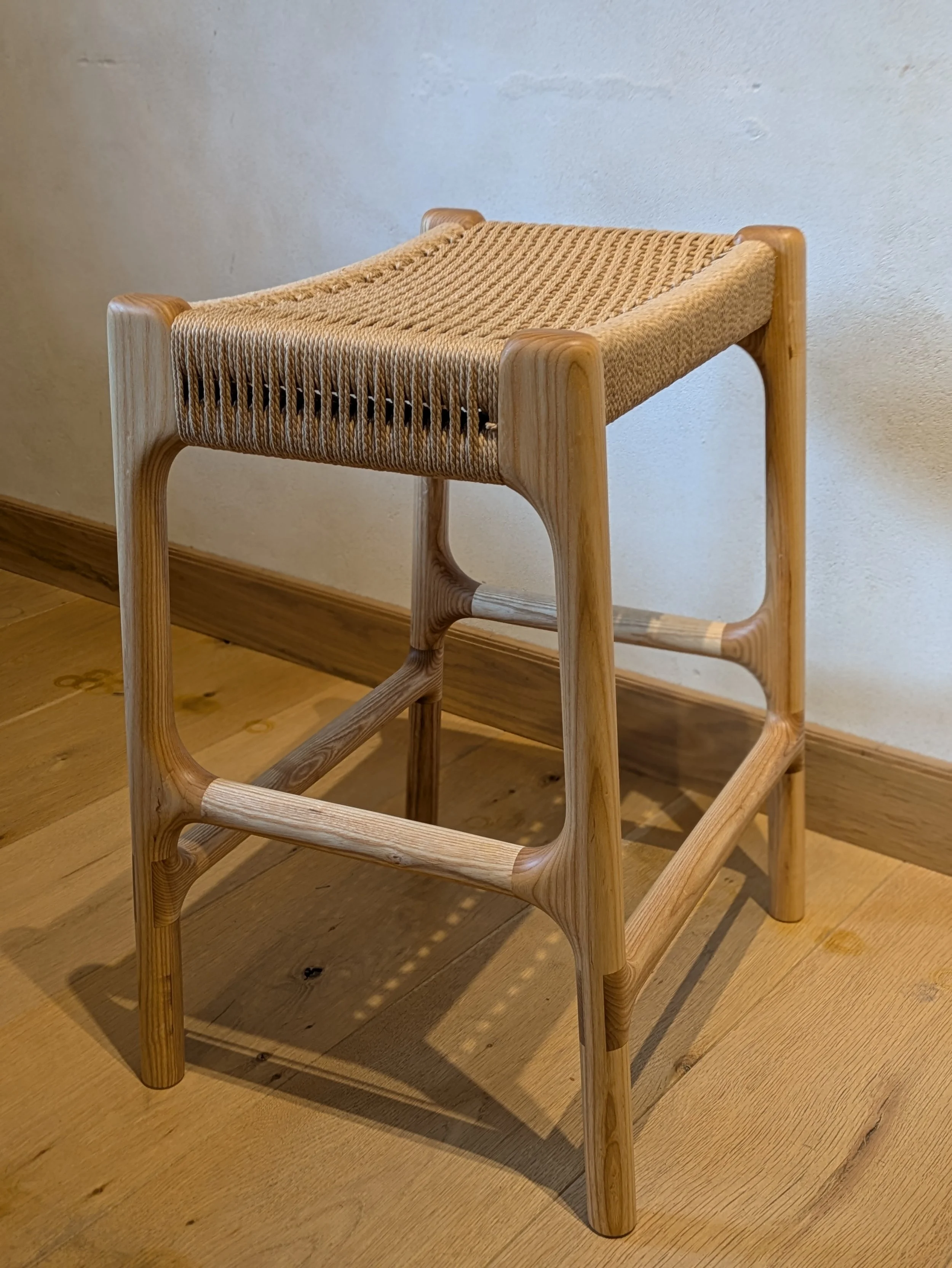 Handcrafted Rast counter stool with curved footrest stretcher and Danish cord seat, front angle view