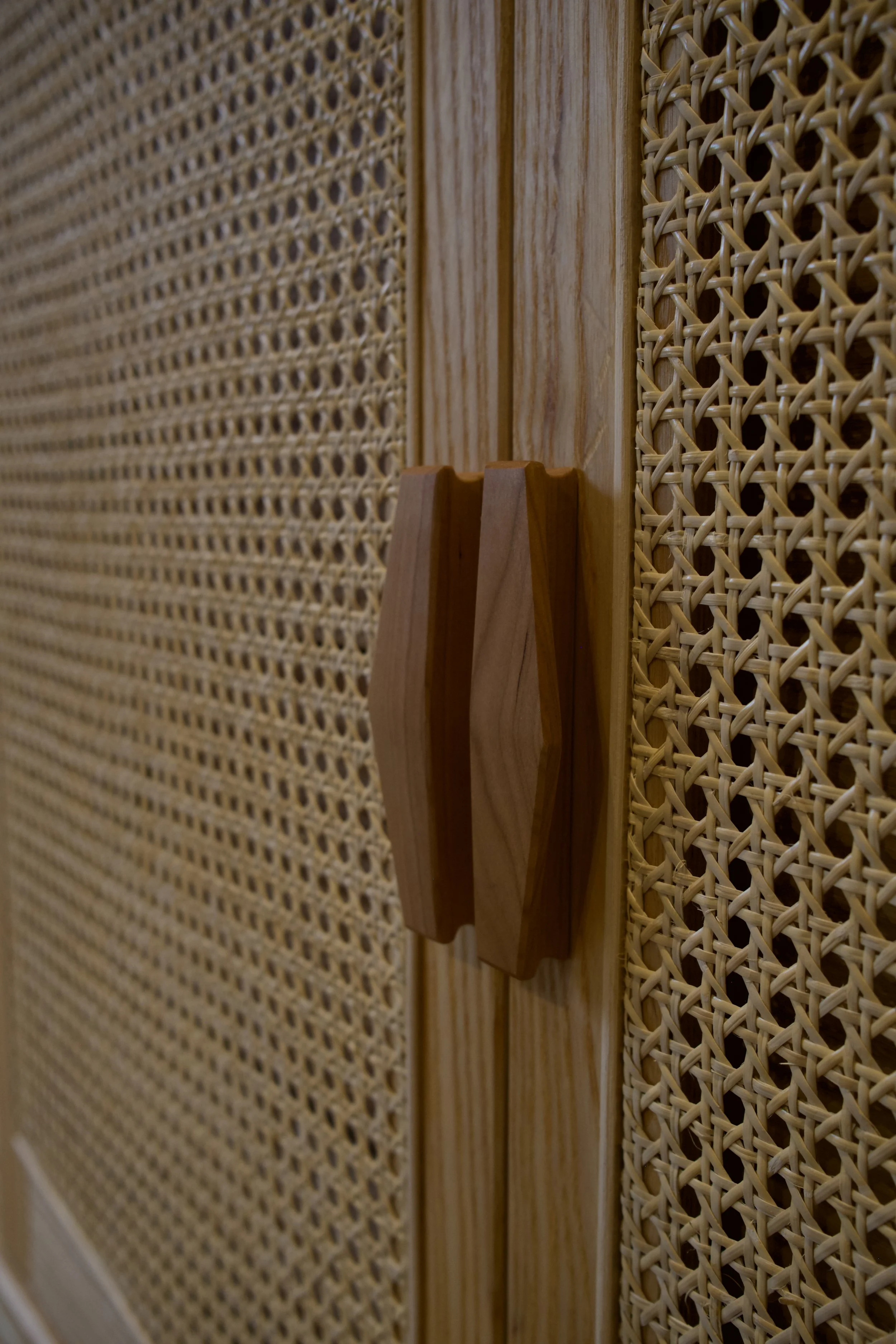 Close-up of a wooden door handle on a rattan-textured door.